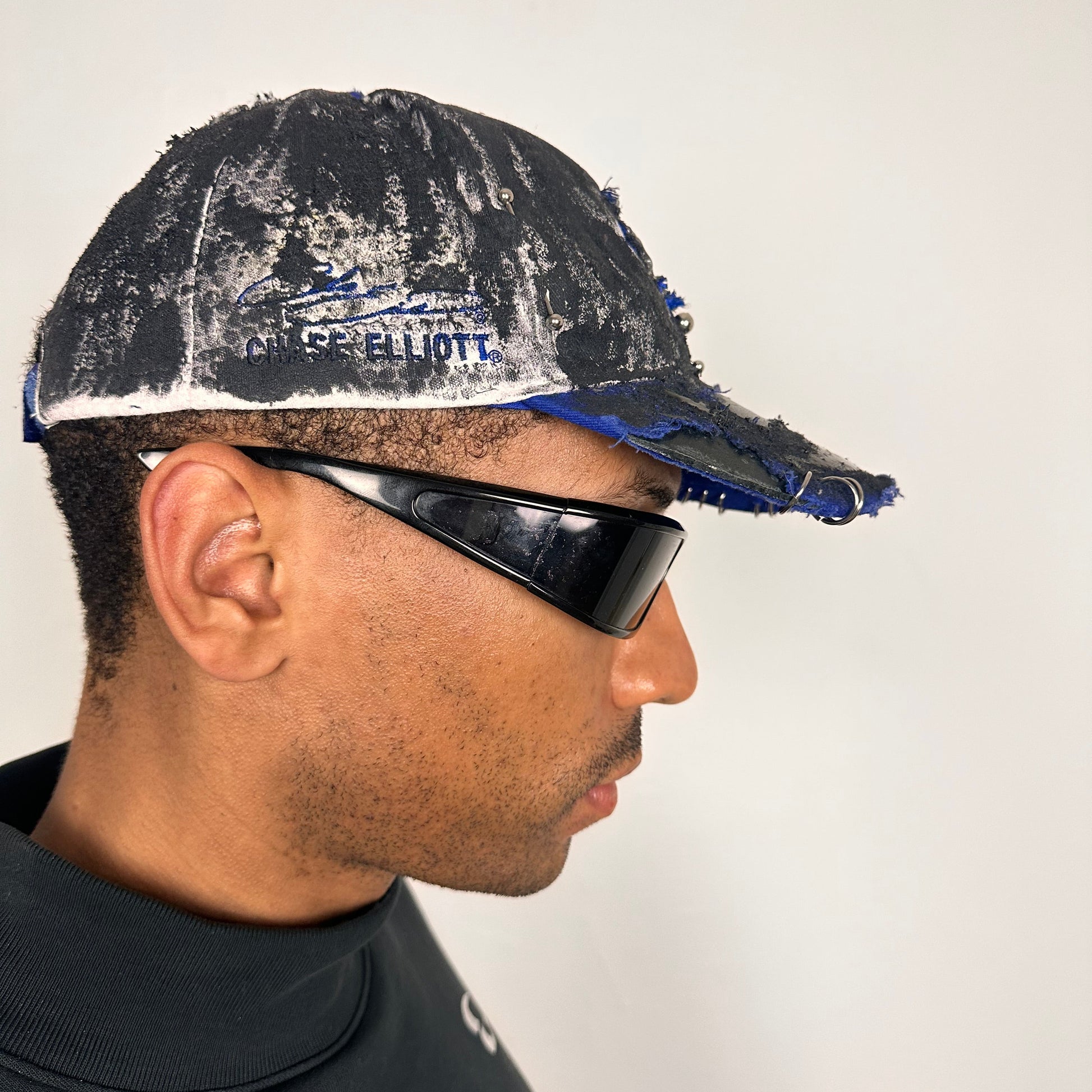 Right side of Blue and white ASTROBOI* NAPA hat with rhinestone-covered logo sealed in clear resin, stainless steel piercings, and a deconstructed visor, handcrafted in NYC.