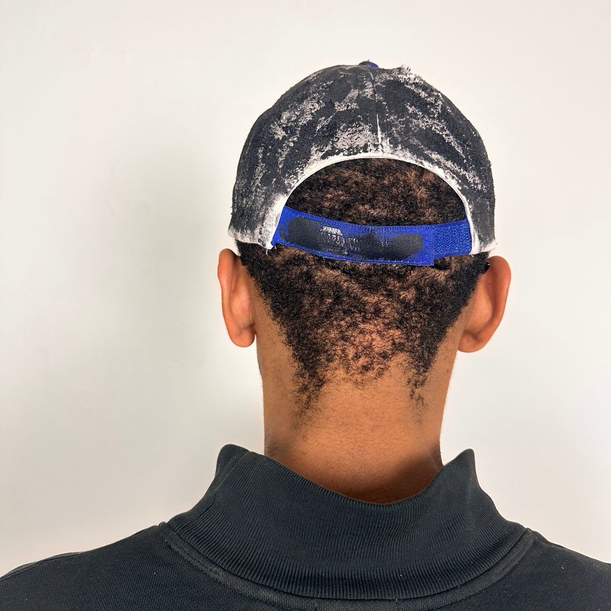 Back side of Blue and white ASTROBOI* NAPA hat with rhinestone-covered logo sealed in clear resin, stainless steel piercings, and a deconstructed visor, handcrafted in NYC.