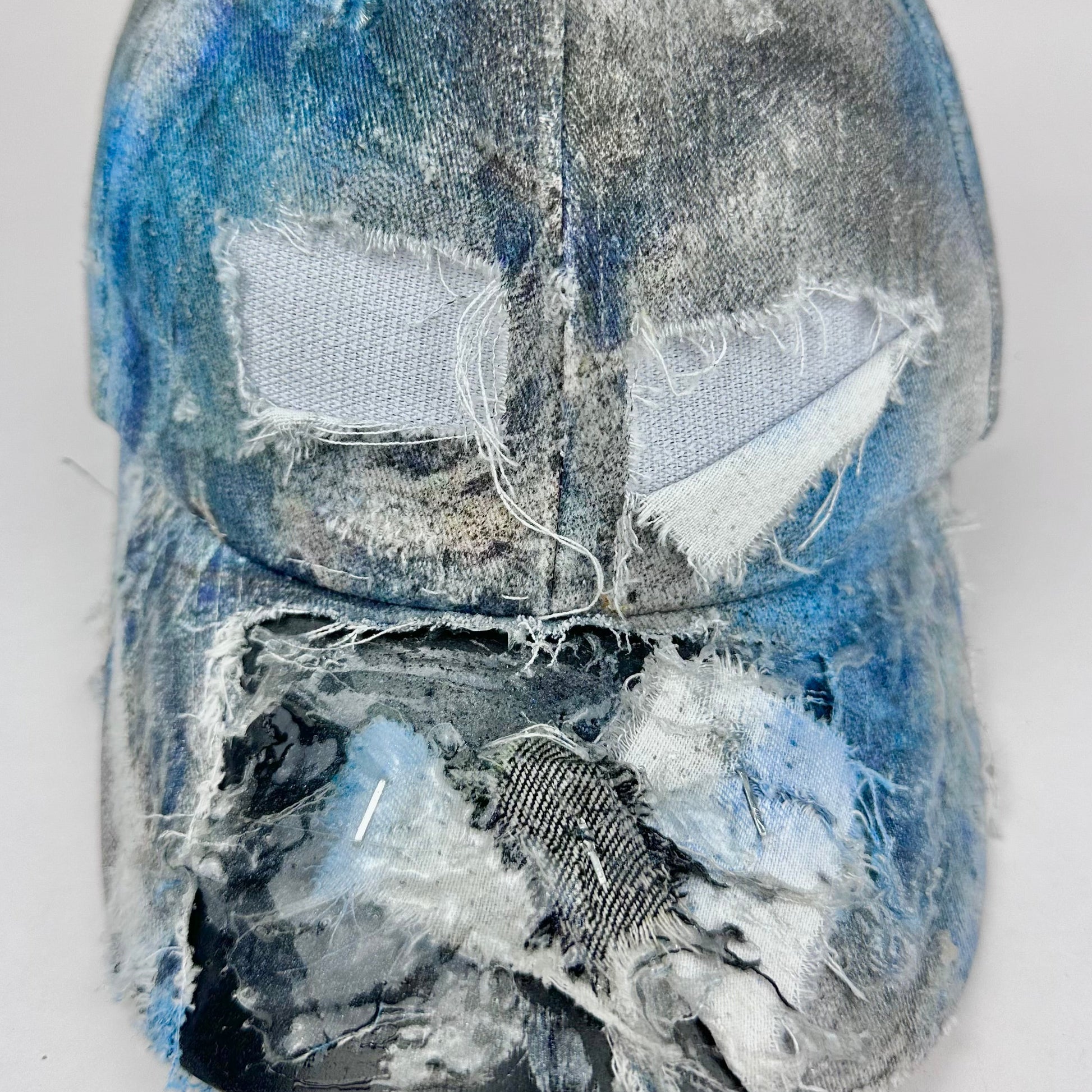 Close up front detail of deconstructed denim print hat with resin