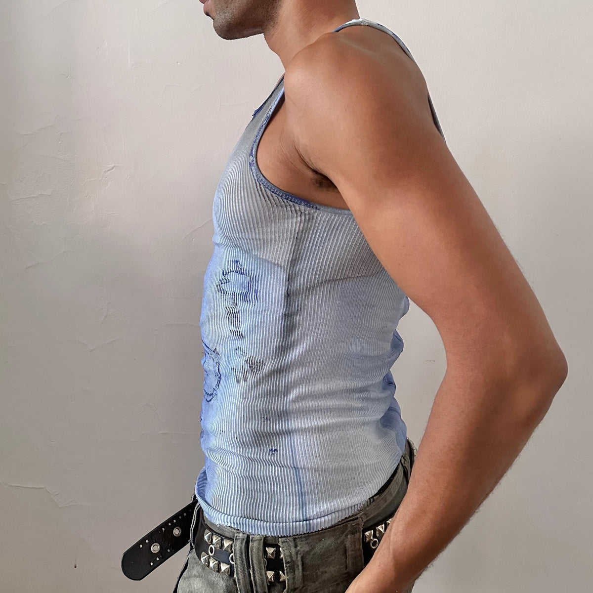 Left side detail of ASTROBOI* x Hanes 'Klein' showing hand-painted blue and black abstract swirl, splatter detail, and raw hemline on white ribbed tank.