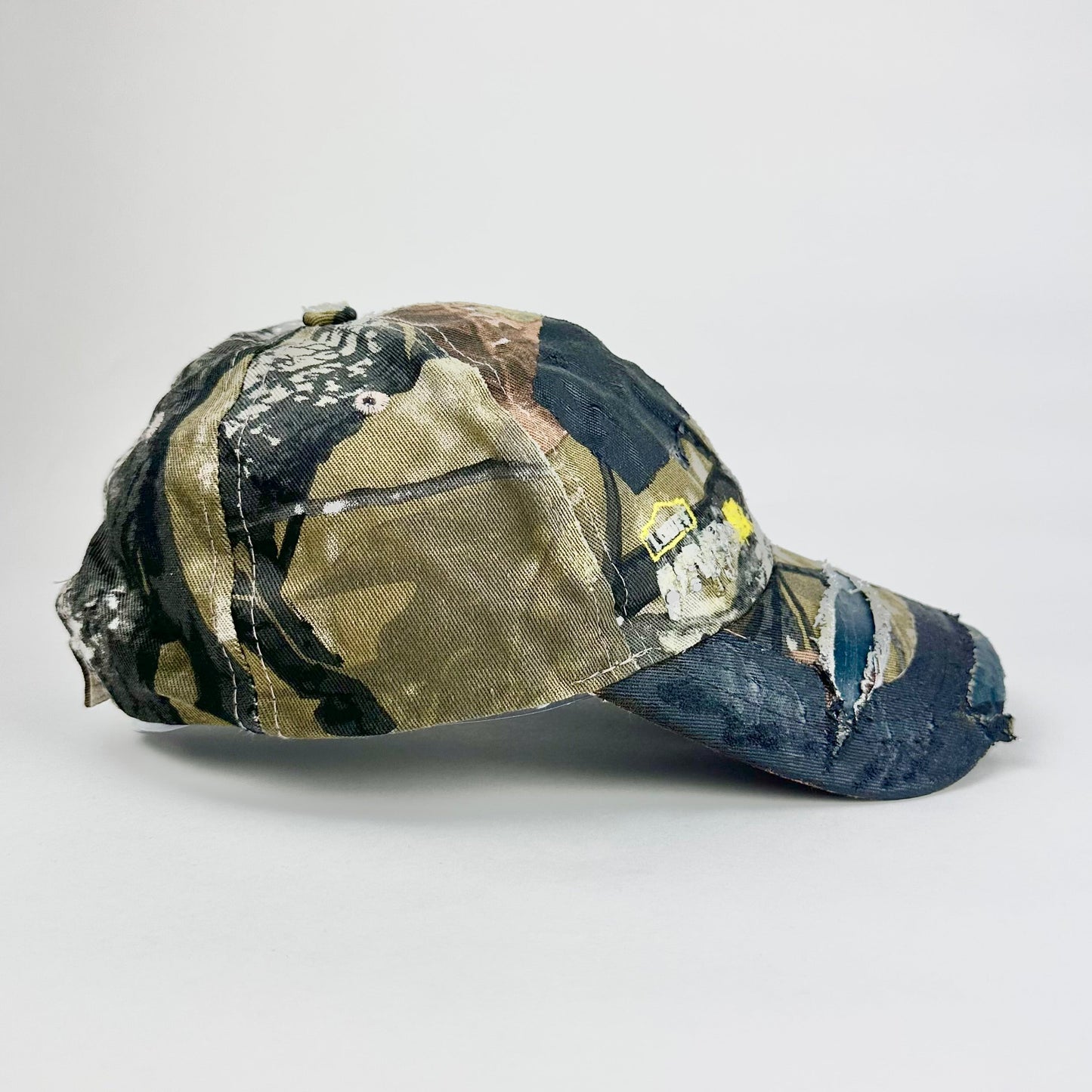 Still life right side of ASTROBOI* x Lowe’s MVP brown RealTree camouflage hat with resin-sealed rhinestone logo, black waxed tattoo print, adjustable strap, custom NYC piece