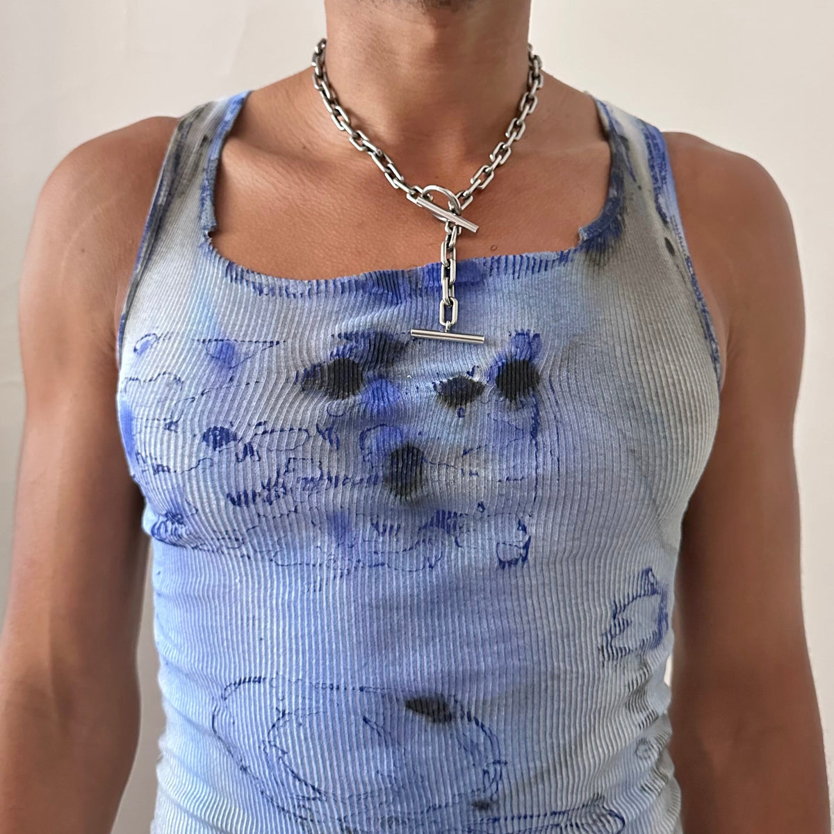 Close-up of ASTROBOI* x Hanes 'Klein' showing blue and black tie dye faded swirl design and paint splatter detail on white ribbed 100% cotton fabric.