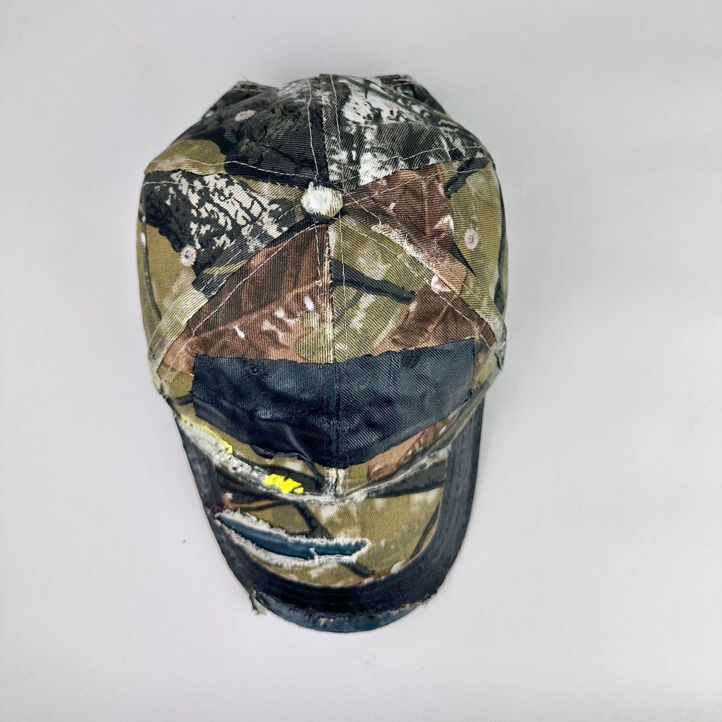 Still life top of ASTROBOI* x Lowe’s MVP brown RealTree camouflage hat with resin-sealed rhinestone logo, black waxed tattoo print, adjustable strap, custom NYC piece