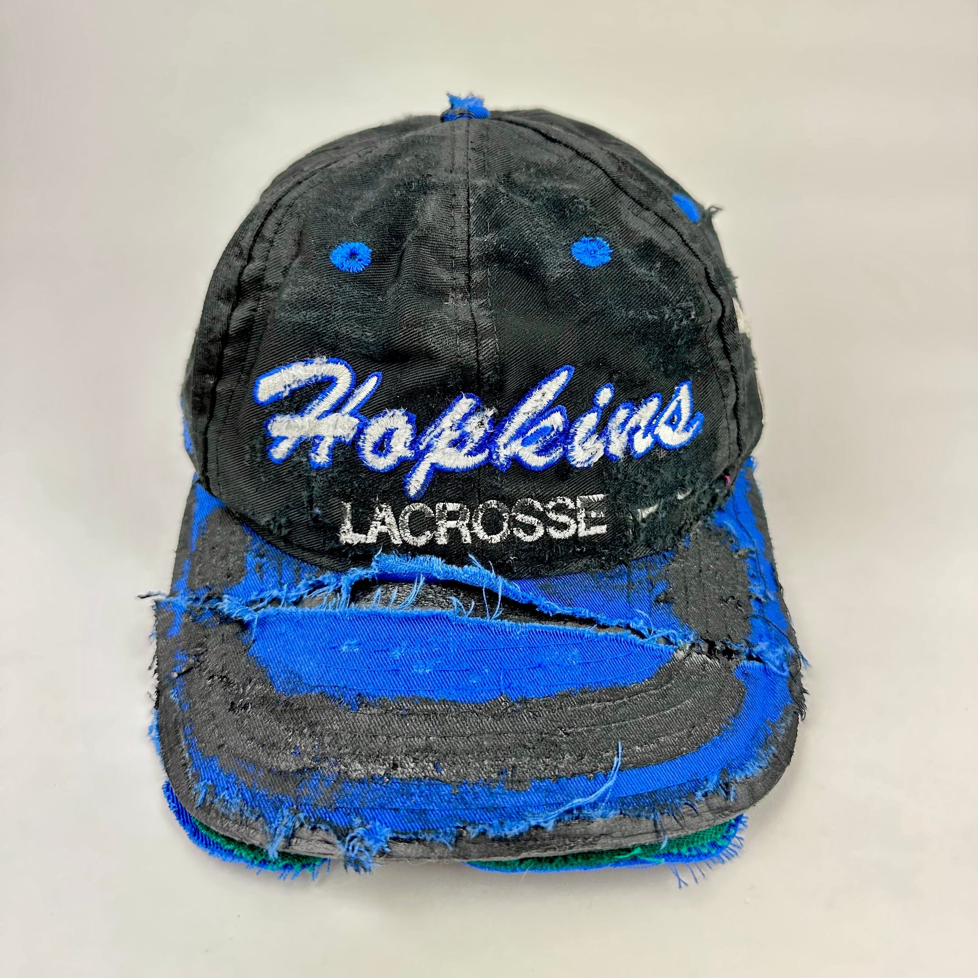 Front 2 of Black distressed ASTROBOI* Hopkins Lacrosse cap with blue embroidery and custom black paint treatment, snapback style, handcrafted in NYC.