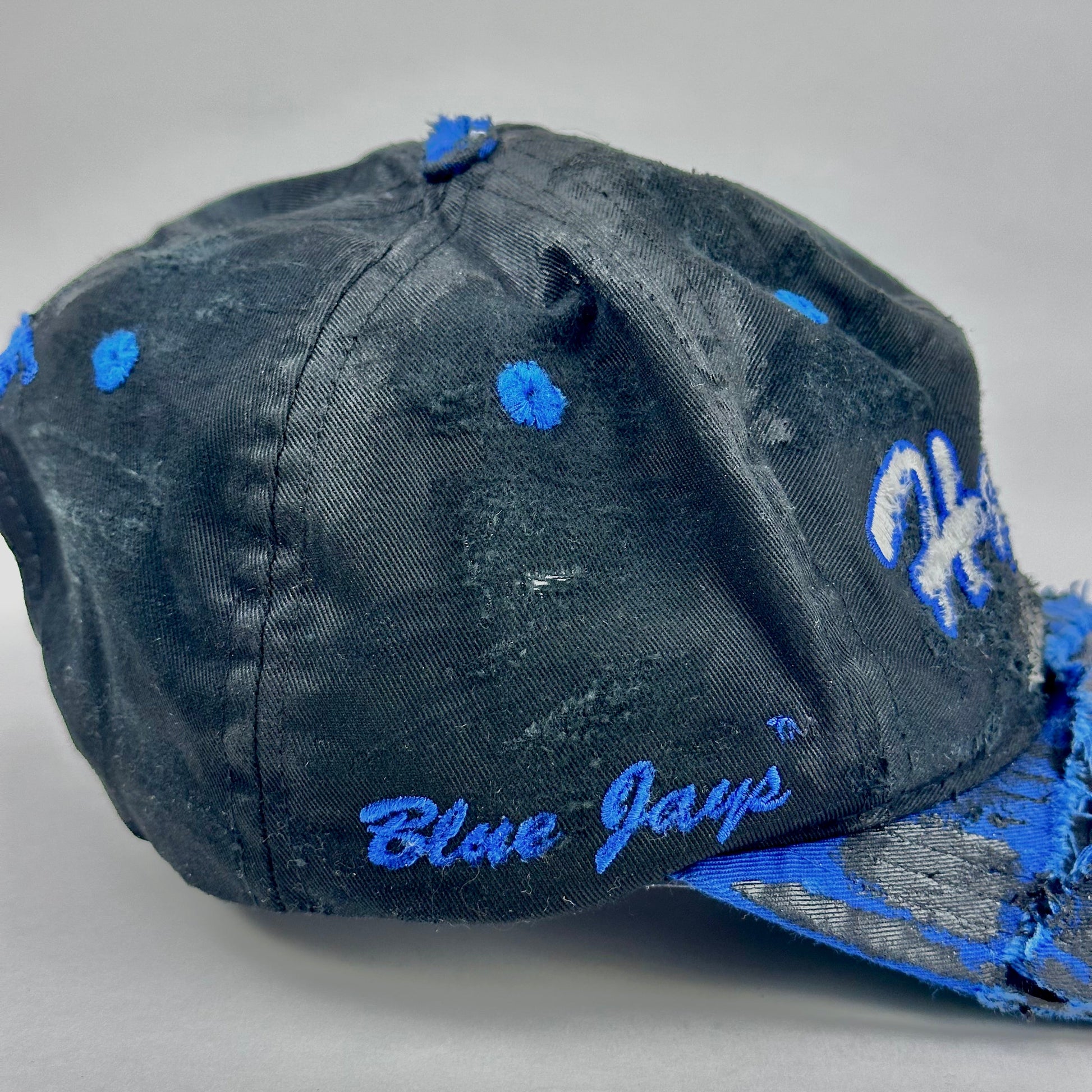 Blue and black cap with 'Blue Jays' text on a gray background
