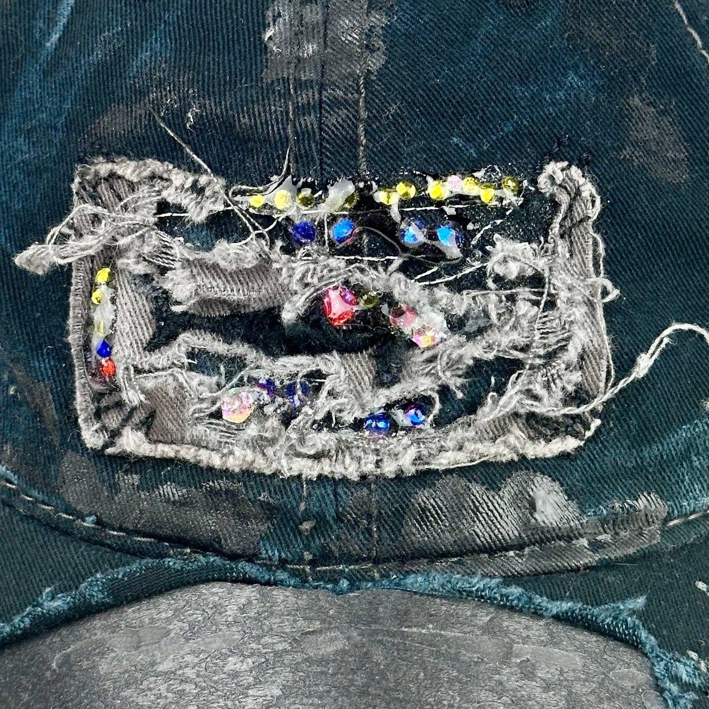 Logo close up product shot of ASTROBOI* New York Aquarium navy distressed baseball hat with resin-sealed rhinestone logo, black waxed paint details, adjustable strap, custom NYC piece