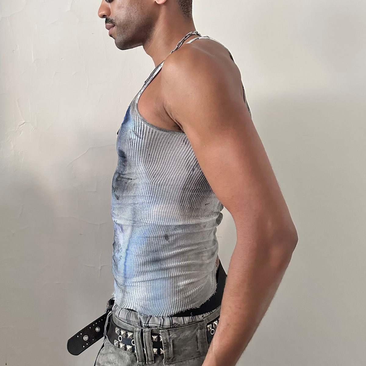 Left side detail of ASTROBOI* x Hanes 'Ice Dancer' showing hand-painted blue and black tribal tattoo print and raw hemline on white ribbed tank.