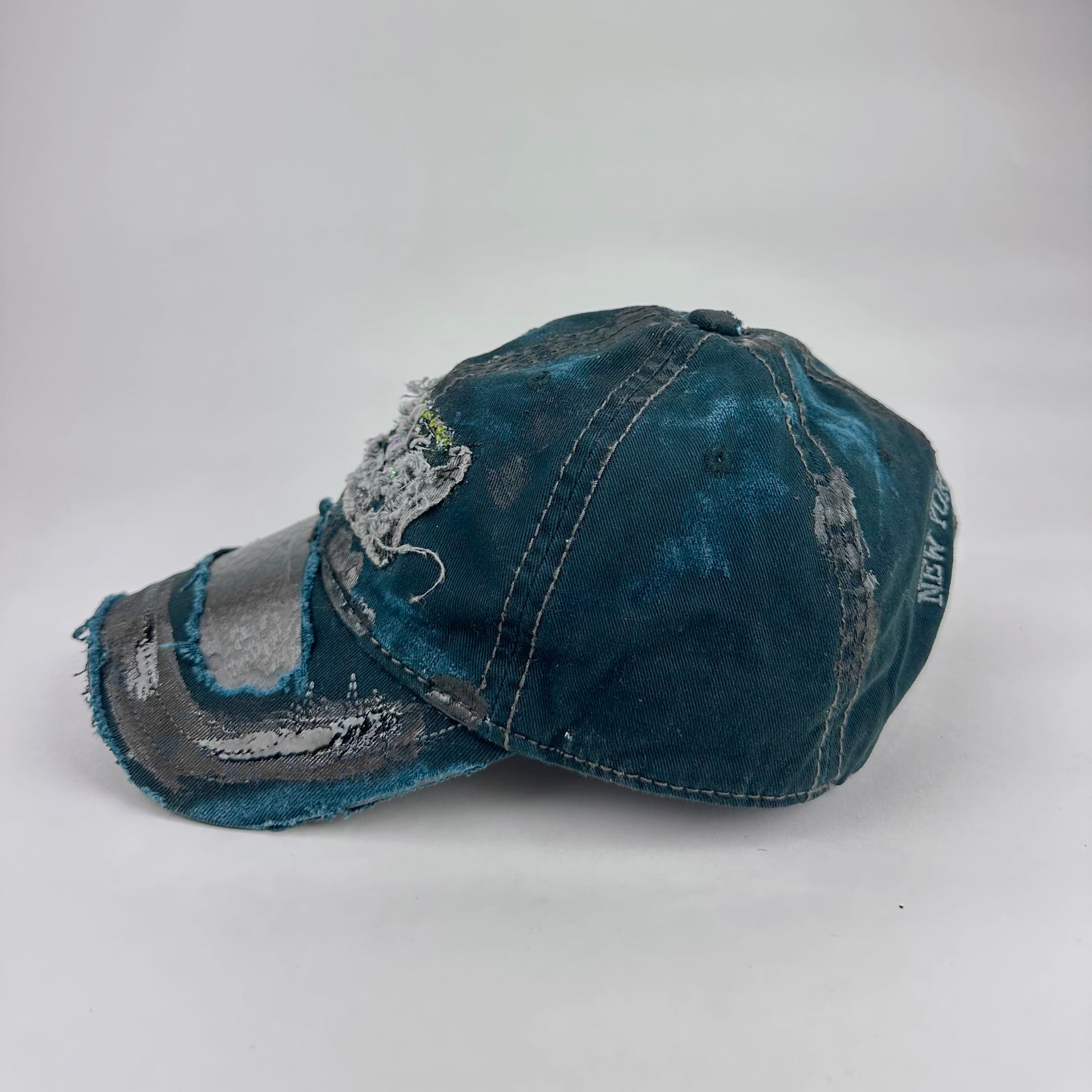 Left side product shot of ASTROBOI* New York Aquarium navy distressed baseball hat with resin-sealed rhinestone logo, black waxed paint details, adjustable strap, custom NYC piece