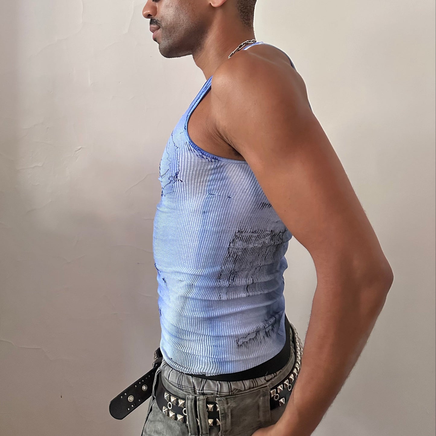 Left side detail of ASTROBOI* x Hanes 'Aero' showing hand-painted blue and black occult swirl design and raw hem detail on white ribbed tank.