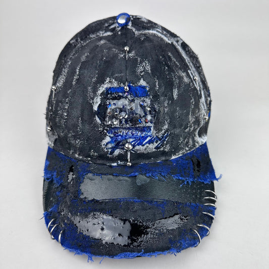 Front of Blue and white ASTROBOI* NAPA hat with rhinestone-covered logo sealed in clear resin, stainless steel piercings, and a deconstructed visor, handcrafted in NYC.
