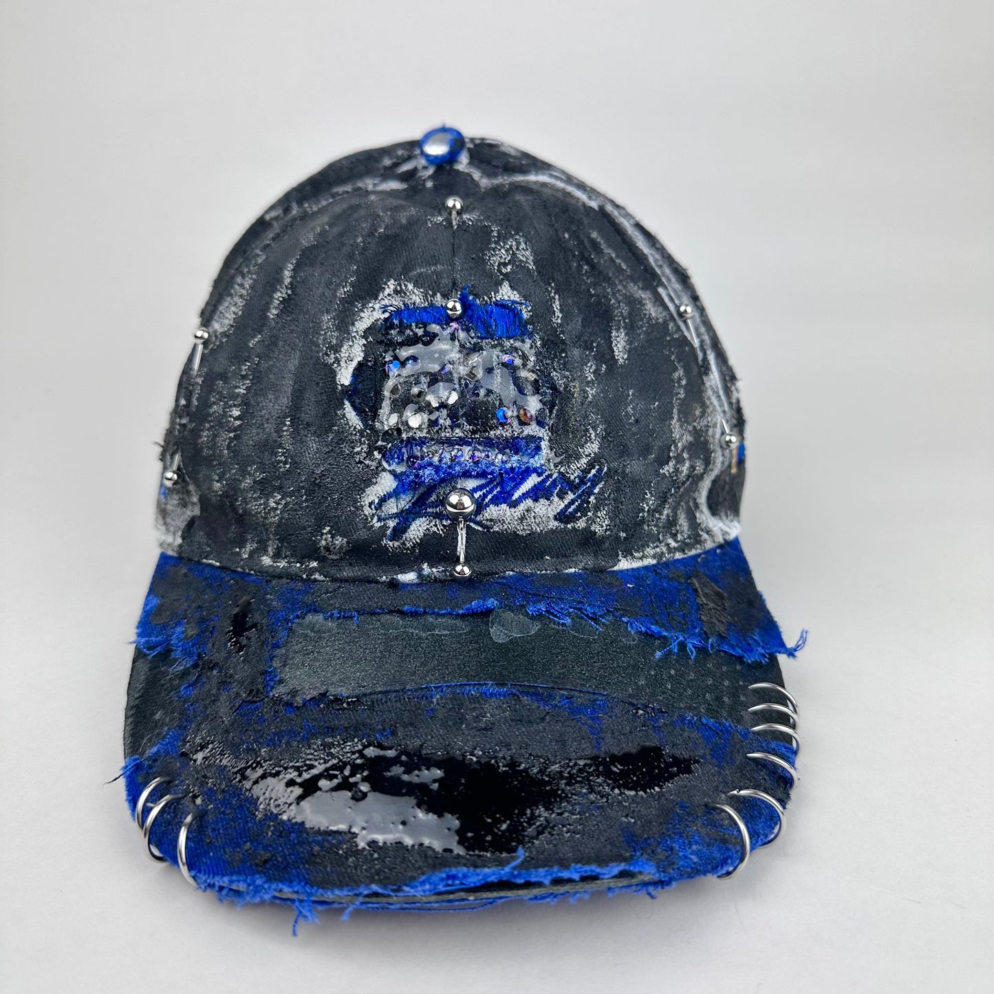 Front image 2 of Blue and white ASTROBOI* NAPA hat with rhinestone-covered logo sealed in clear resin, stainless steel piercings, and a deconstructed visor, handcrafted in NYC.