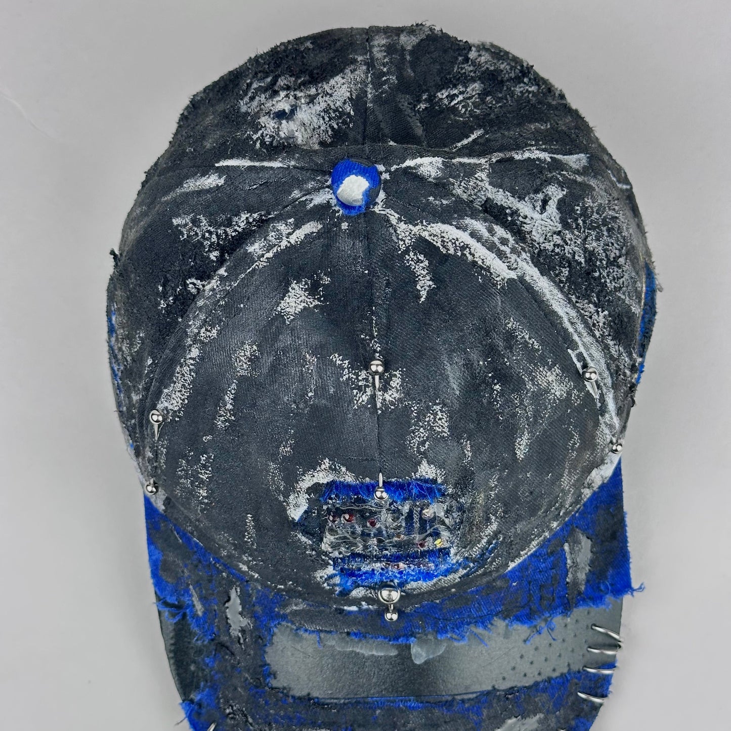 Top view of Blue and white ASTROBOI* NAPA hat with rhinestone-covered logo sealed in clear resin, stainless steel piercings, and a deconstructed visor, handcrafted in NYC.
