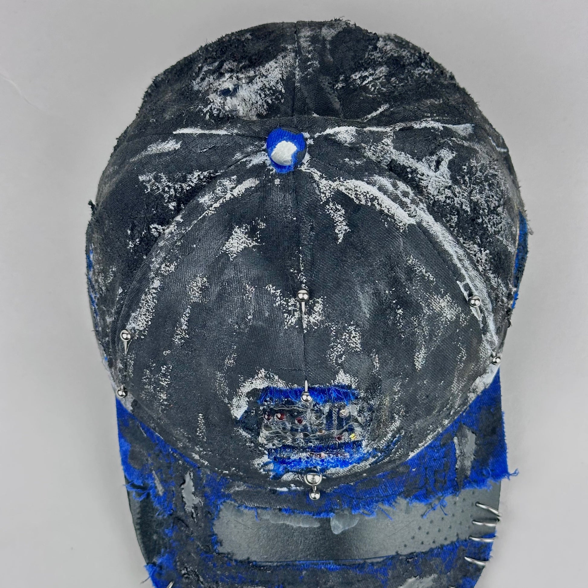 Top view of Blue and white ASTROBOI* NAPA hat with rhinestone-covered logo sealed in clear resin, stainless steel piercings, and a deconstructed visor, handcrafted in NYC.