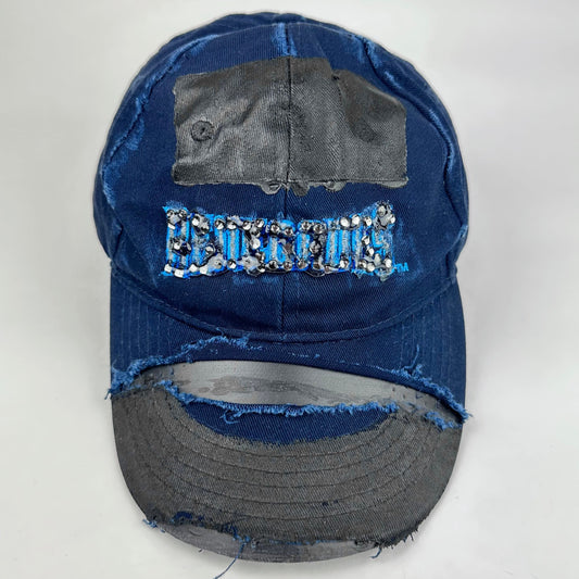 Front product shot of ASTROBOI* x Renegades navy distressed hat with resin-sealed rhinestones and tattoo-style paint details. One-of-one custom piece made in NYC.