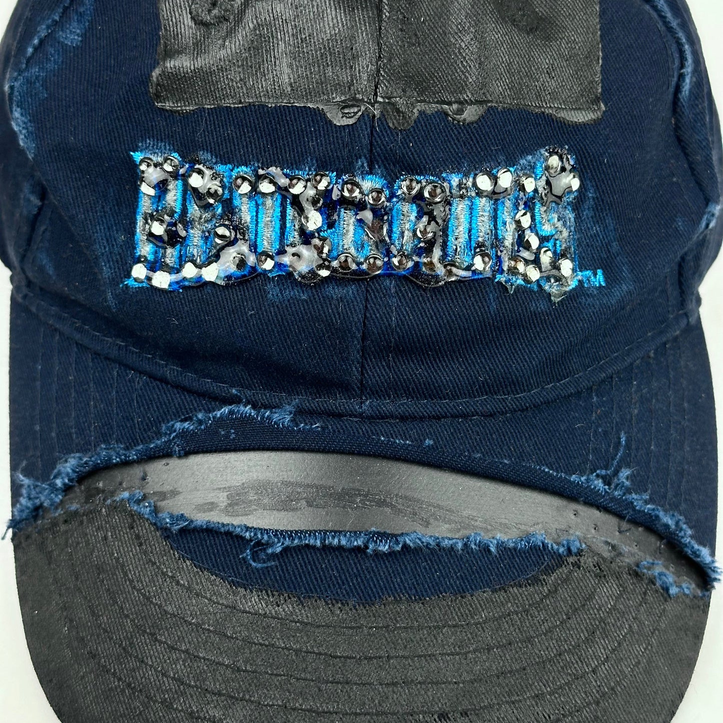 Close up product shot of ASTROBOI* x Renegades navy distressed hat with resin-sealed rhinestones and tattoo-style paint details. One-of-one custom piece made in NYC.