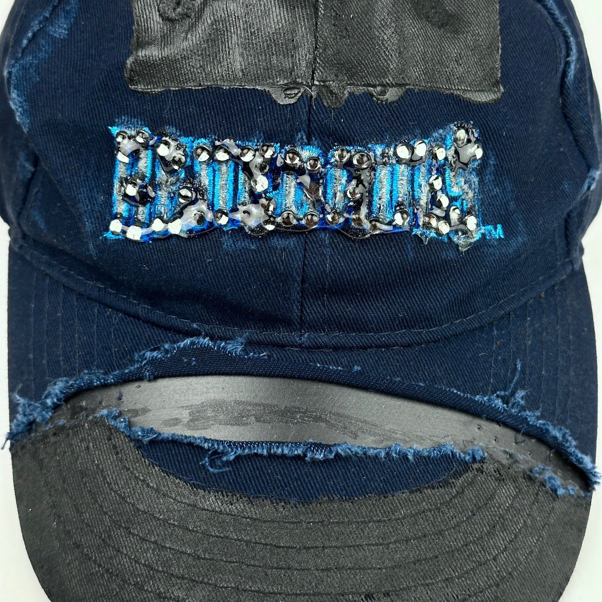 Close up product shot of ASTROBOI* x Renegades navy distressed hat with resin-sealed rhinestones and tattoo-style paint details. One-of-one custom piece made in NYC.