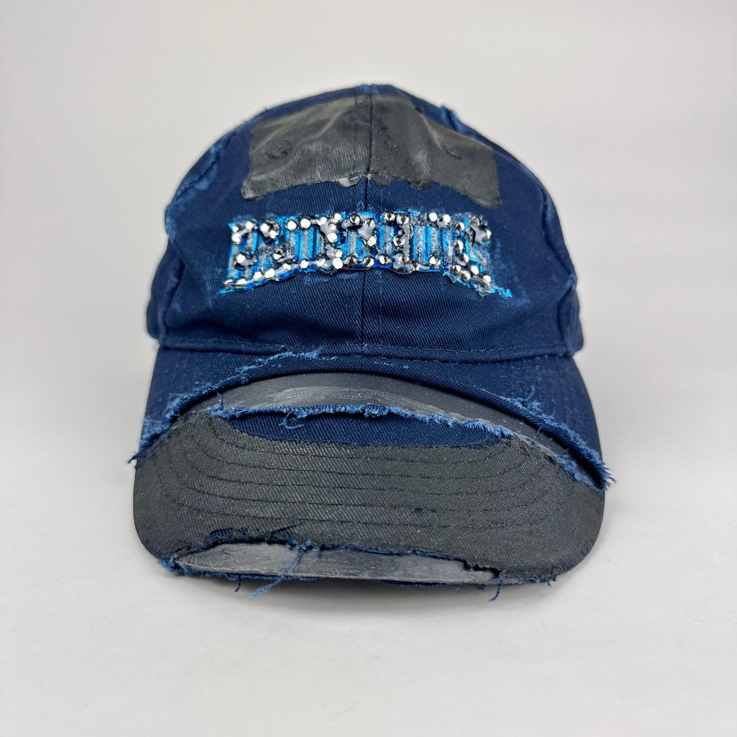 Overview product shot of ASTROBOI* x Renegades navy distressed hat with resin-sealed rhinestones and tattoo-style paint details. One-of-one custom piece made in NYC.