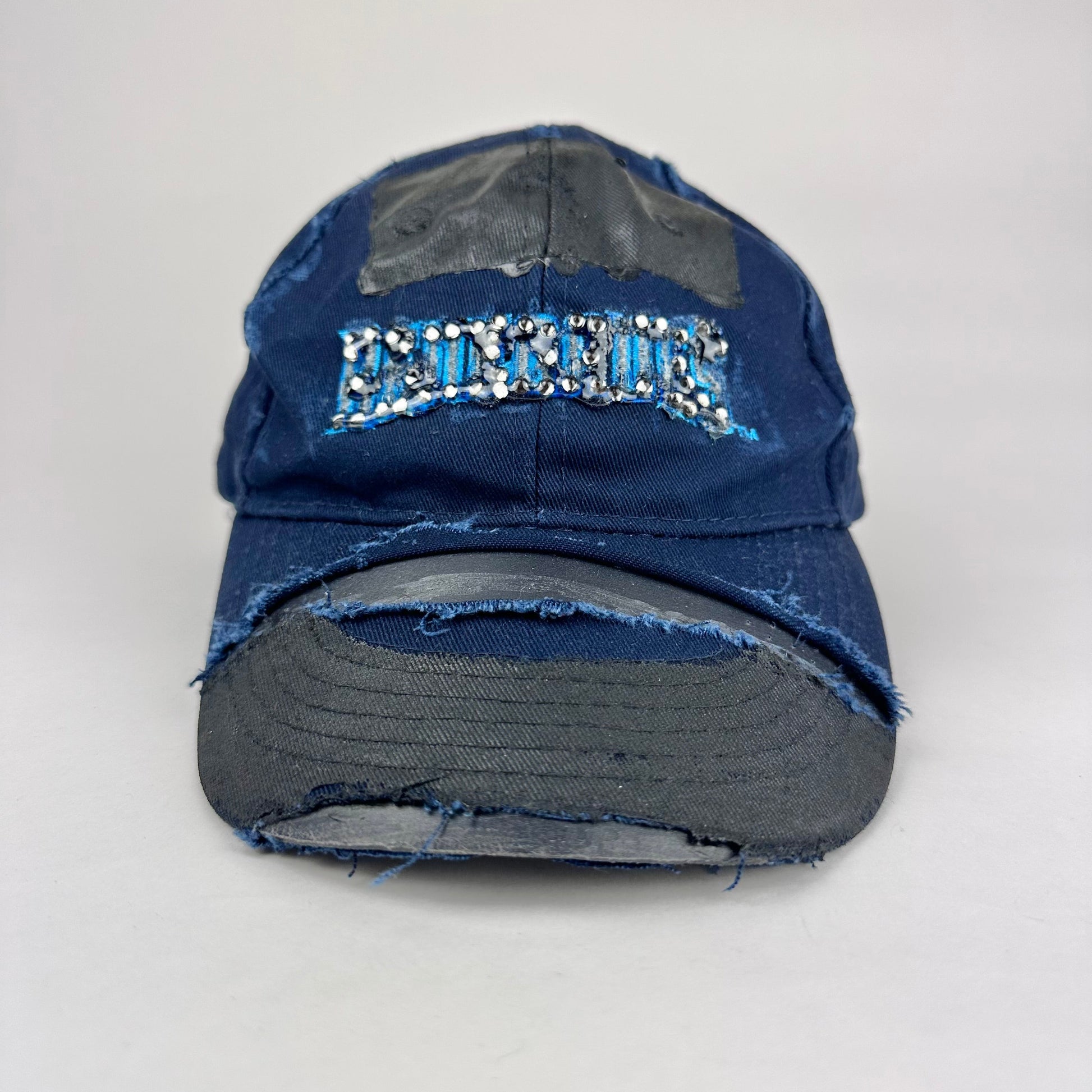 Overview product shot of ASTROBOI* x Renegades navy distressed hat with resin-sealed rhinestones and tattoo-style paint details. One-of-one custom piece made in NYC.