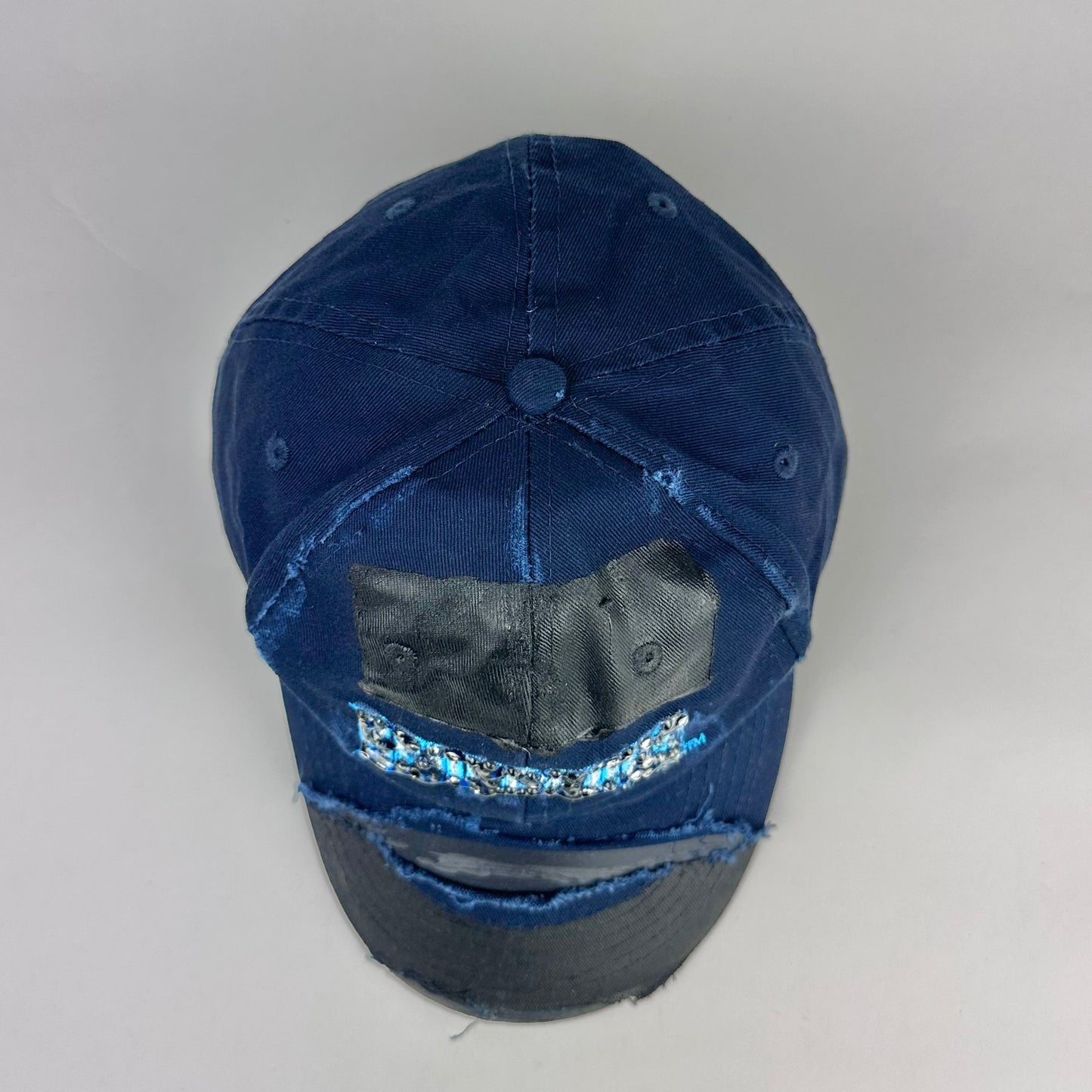 Top product shot of ASTROBOI* x Renegades navy distressed hat with resin-sealed rhinestones and tattoo-style paint details. One-of-one custom piece made in NYC.