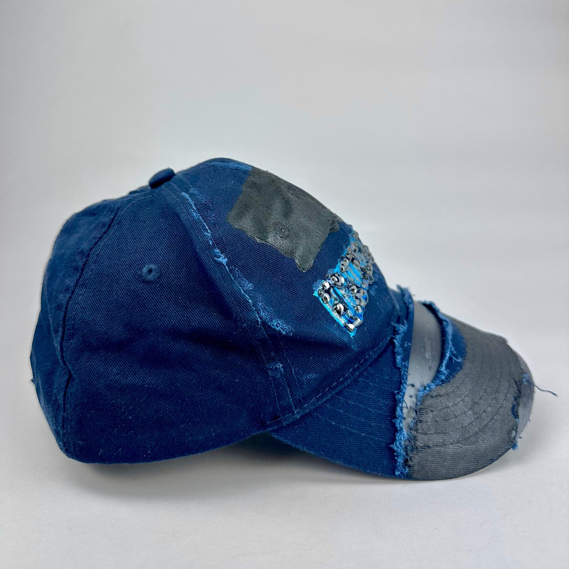 Right side product shot of ASTROBOI* x Renegades navy distressed hat with resin-sealed rhinestones and tattoo-style paint details. One-of-one custom piece made in NYC.