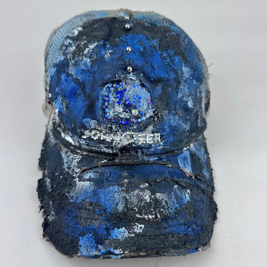 Frontal project shot image of ASTROBOI* x John Deere black and blue distressed trucker hat with rhinestone resin logo and stainless steel piercings.