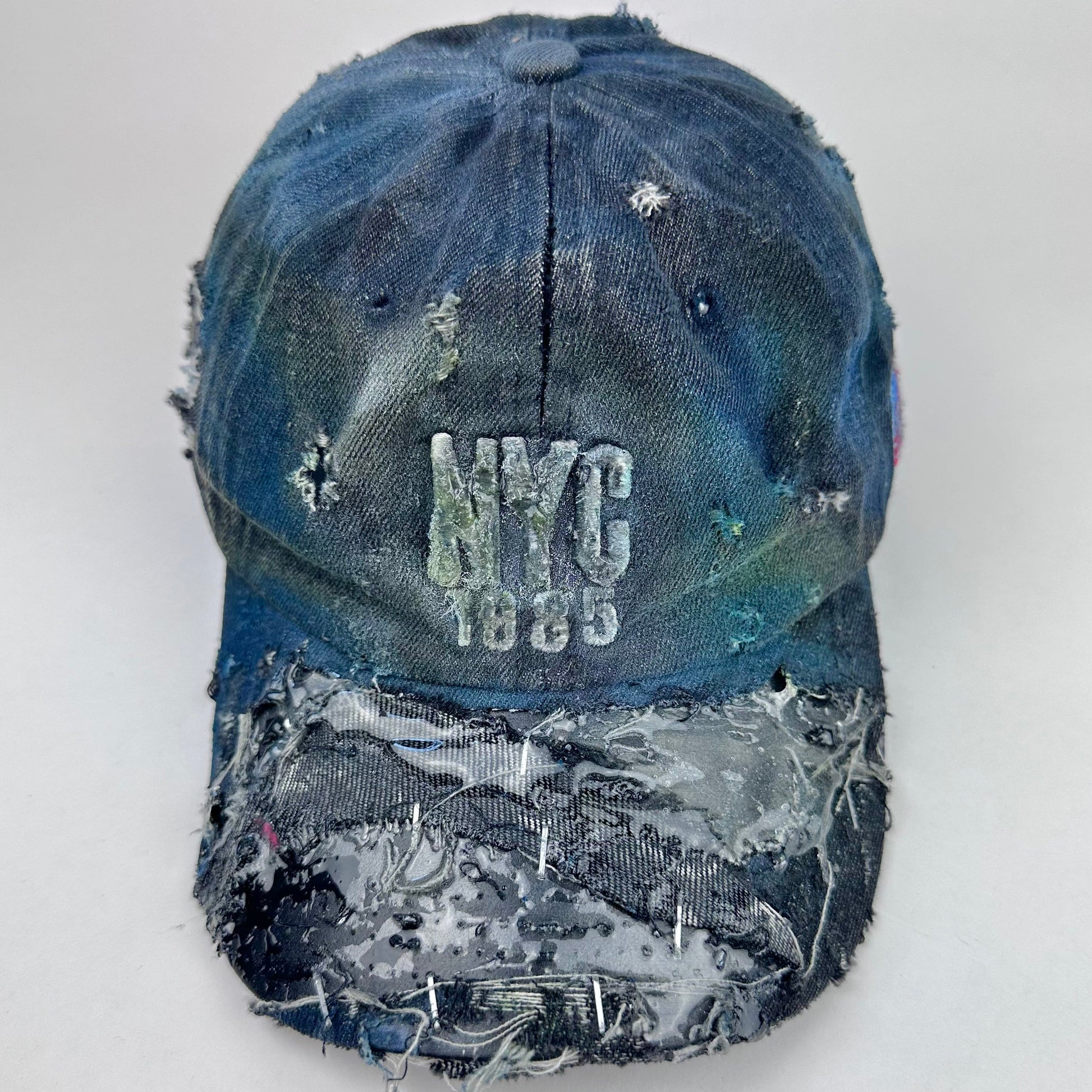 Distressed blue cap with 'NYC 1985' text on a white background
