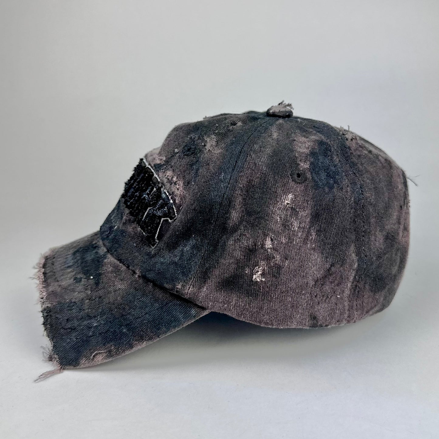 Left side on ASTROBOI* New York brown and black distressed half-visor hat with bold logo, black paint accents, and deconstructed grunge design. Handmade in NYC.