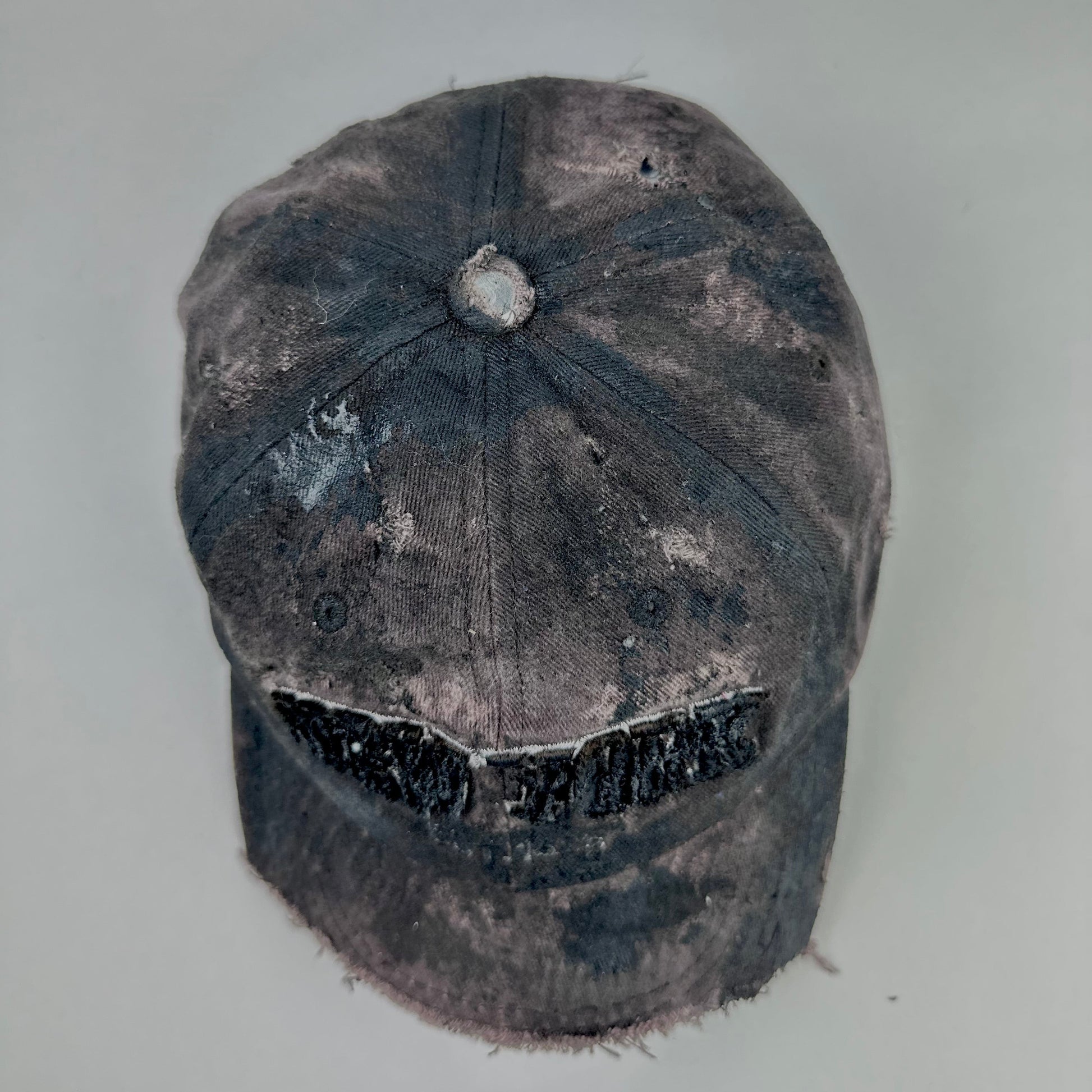 Top of ASTROBOI* New York brown and black distressed half-visor hat with bold logo, black paint accents, and deconstructed grunge design. Handmade in NYC.