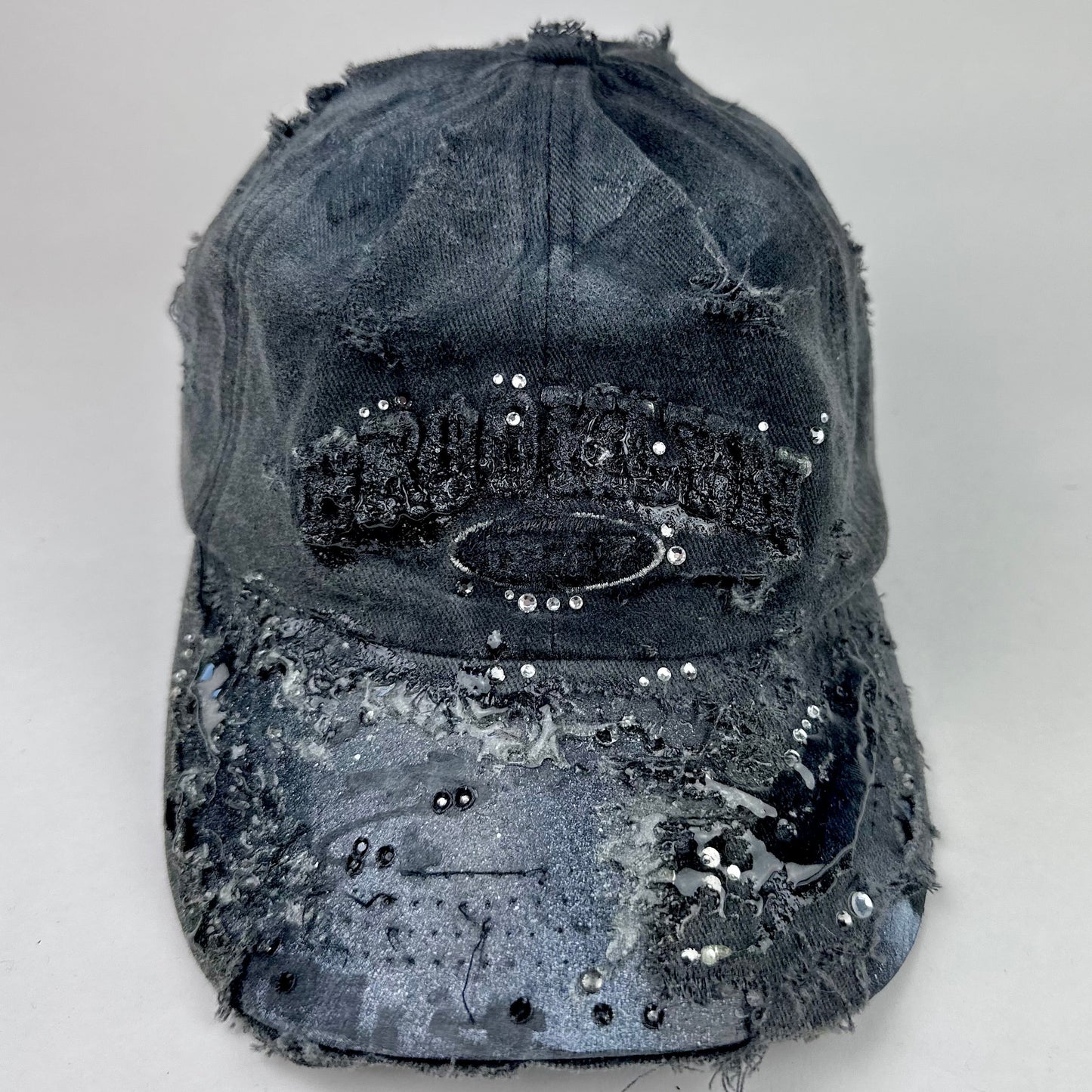 Front of ASTROBOI* 'Alastair' black distressed resin hat with clear resin-encased Brooklyn logo at center front, silver rhinestone embellishments, and custom black resin detailing, handcrafted in NYC.