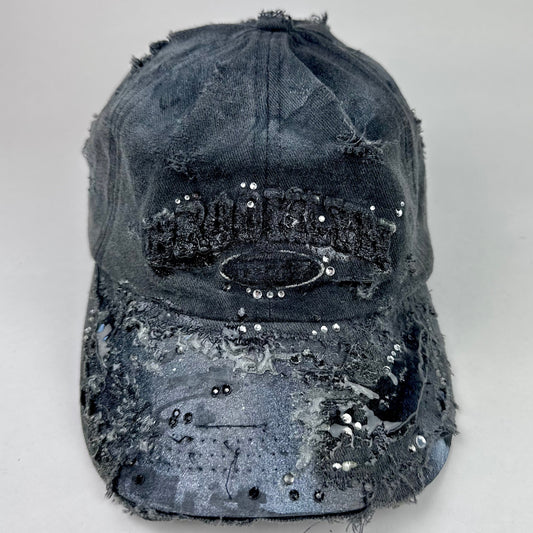 Front of ASTROBOI* 'Alastair' black distressed resin hat with clear resin-encased Brooklyn logo at center front, silver rhinestone embellishments, and custom black resin detailing, handcrafted in NYC.