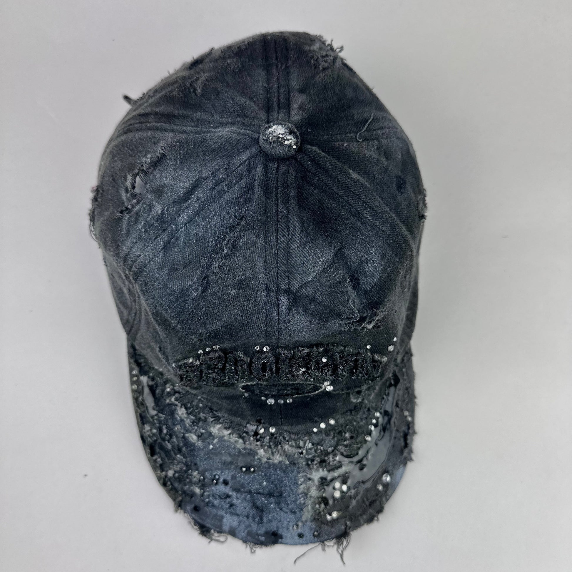 Top of ASTROBOI* 'Alastair' black distressed resin hat with clear resin-encased Brooklyn logo at center front, silver rhinestone embellishments, and custom black resin detailing, handcrafted in NYC.