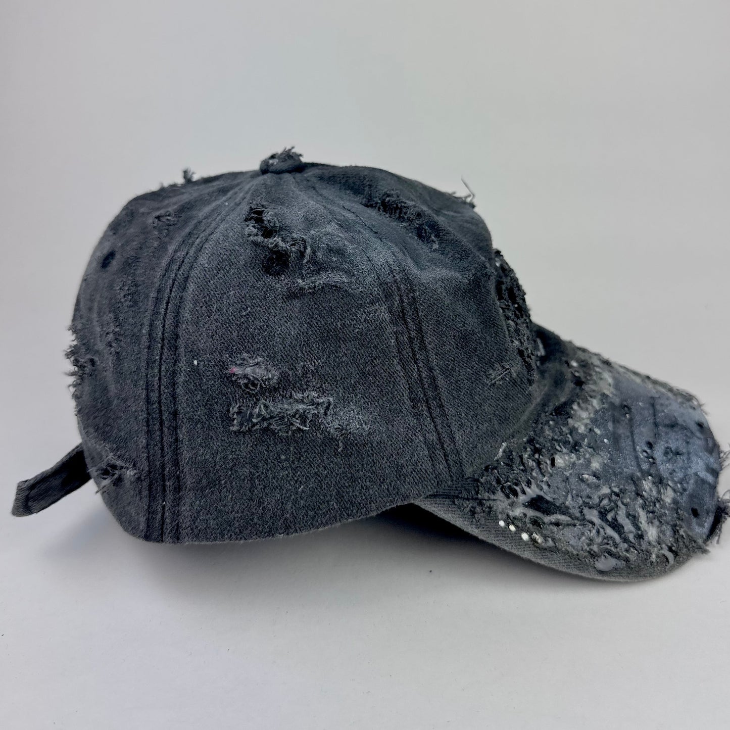 Right side of ASTROBOI* 'Alastair' black distressed resin hat with clear resin-encased Brooklyn logo at center front, silver rhinestone embellishments, and custom black resin detailing, handcrafted in NYC.