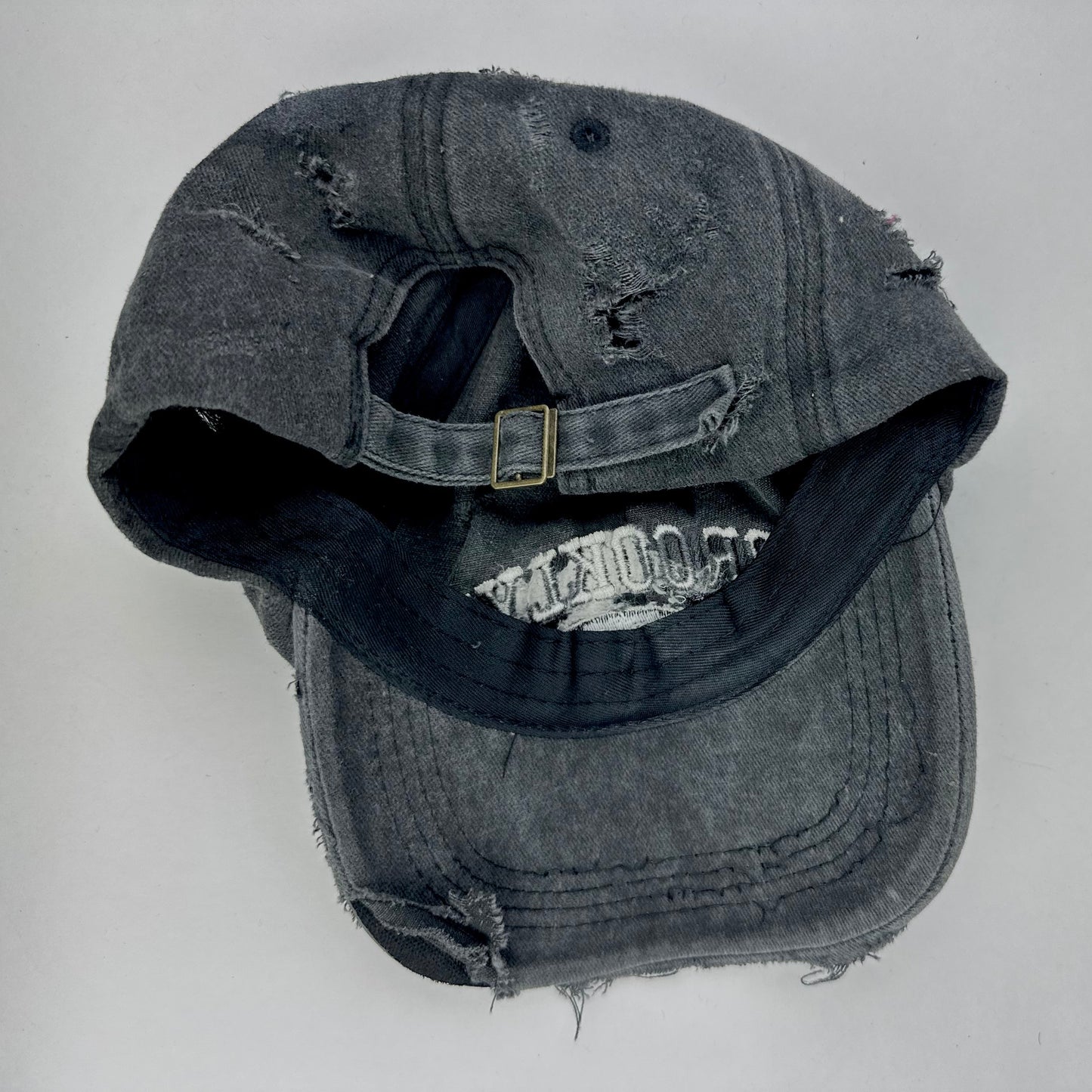 Back of ASTROBOI* 'Alastair' black distressed resin hat with clear resin-encased Brooklyn logo at center front, silver rhinestone embellishments, and custom black resin detailing, handcrafted in NYC.