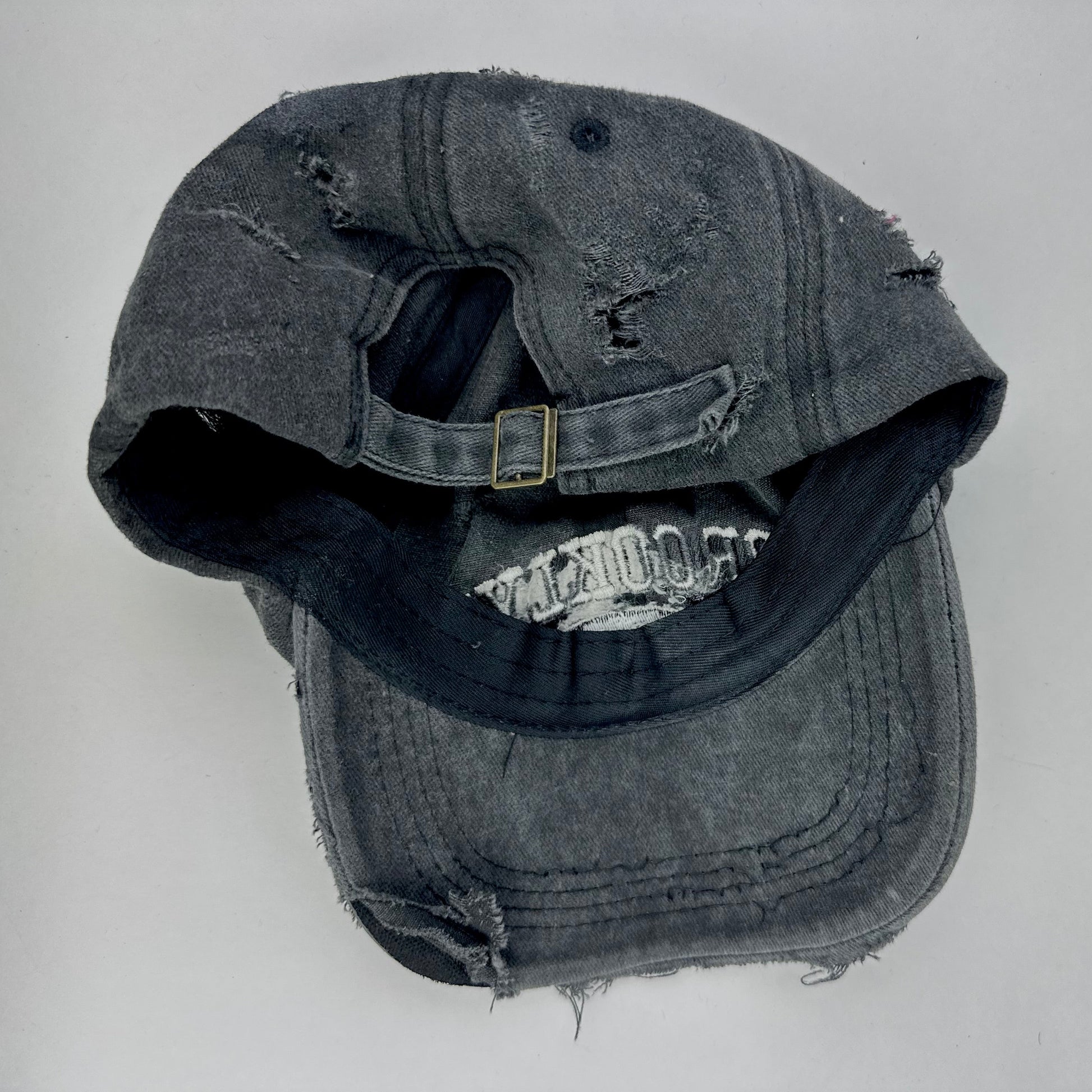Back of ASTROBOI* 'Alastair' black distressed resin hat with clear resin-encased Brooklyn logo at center front, silver rhinestone embellishments, and custom black resin detailing, handcrafted in NYC.