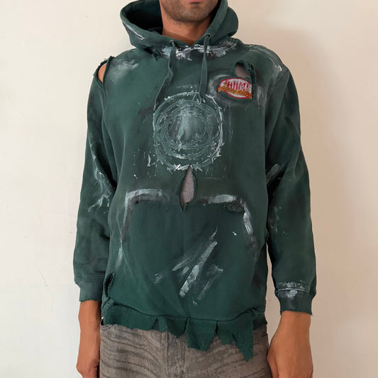 ASTROBOI* ‘Otis’ green loose-fitting painted barbed wire utility hoodie with white faded barbed wire design at chest, white and black paint details, holes, and deconstructed kangaroo pocket with raw uneven hem, front view.