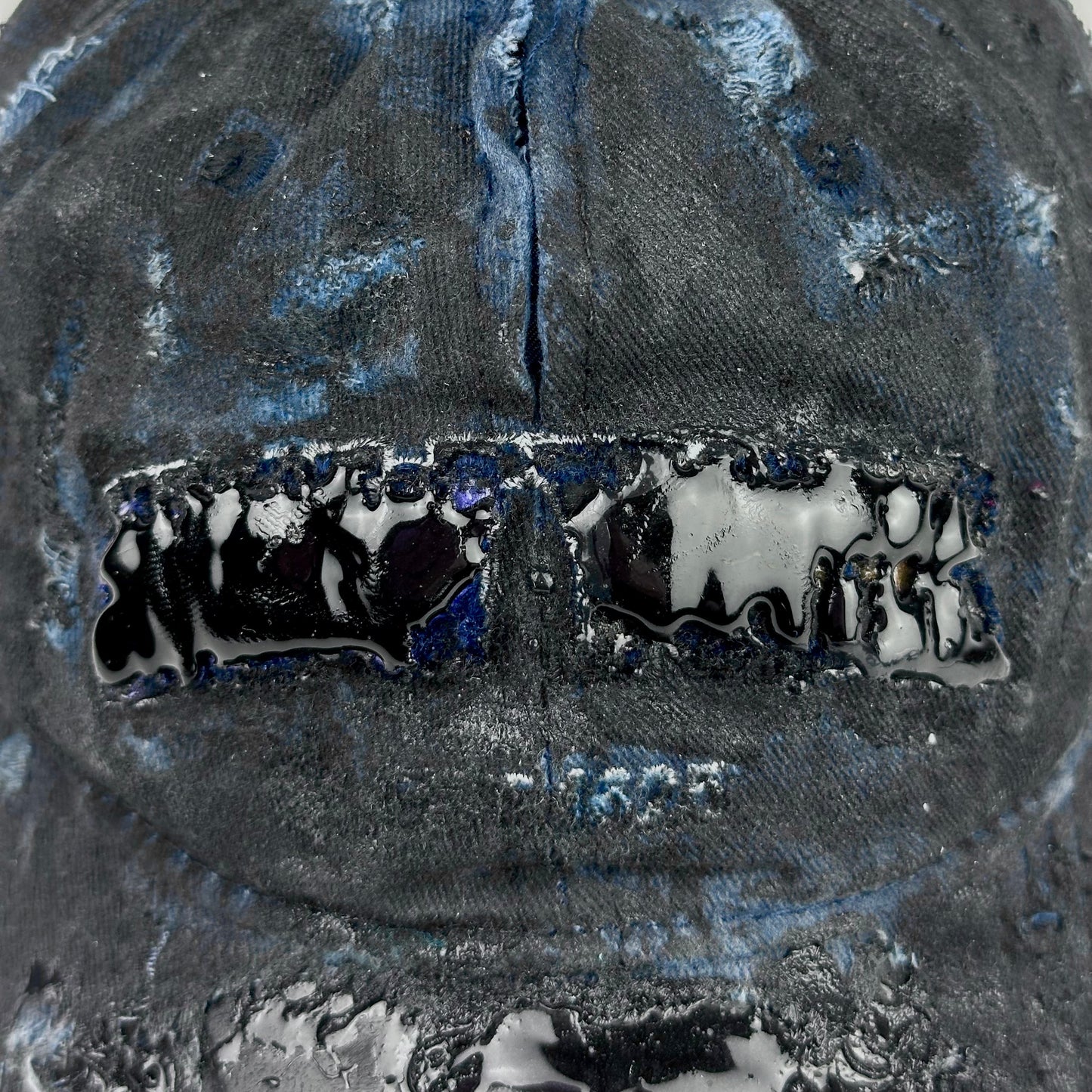 Logo detail on ASTROBOI* 'Feeling Blue' distressed blue resin-coated hat with hand-painted black shading, metal piercings on the right front, and New York embroidery, handmade in NYC.