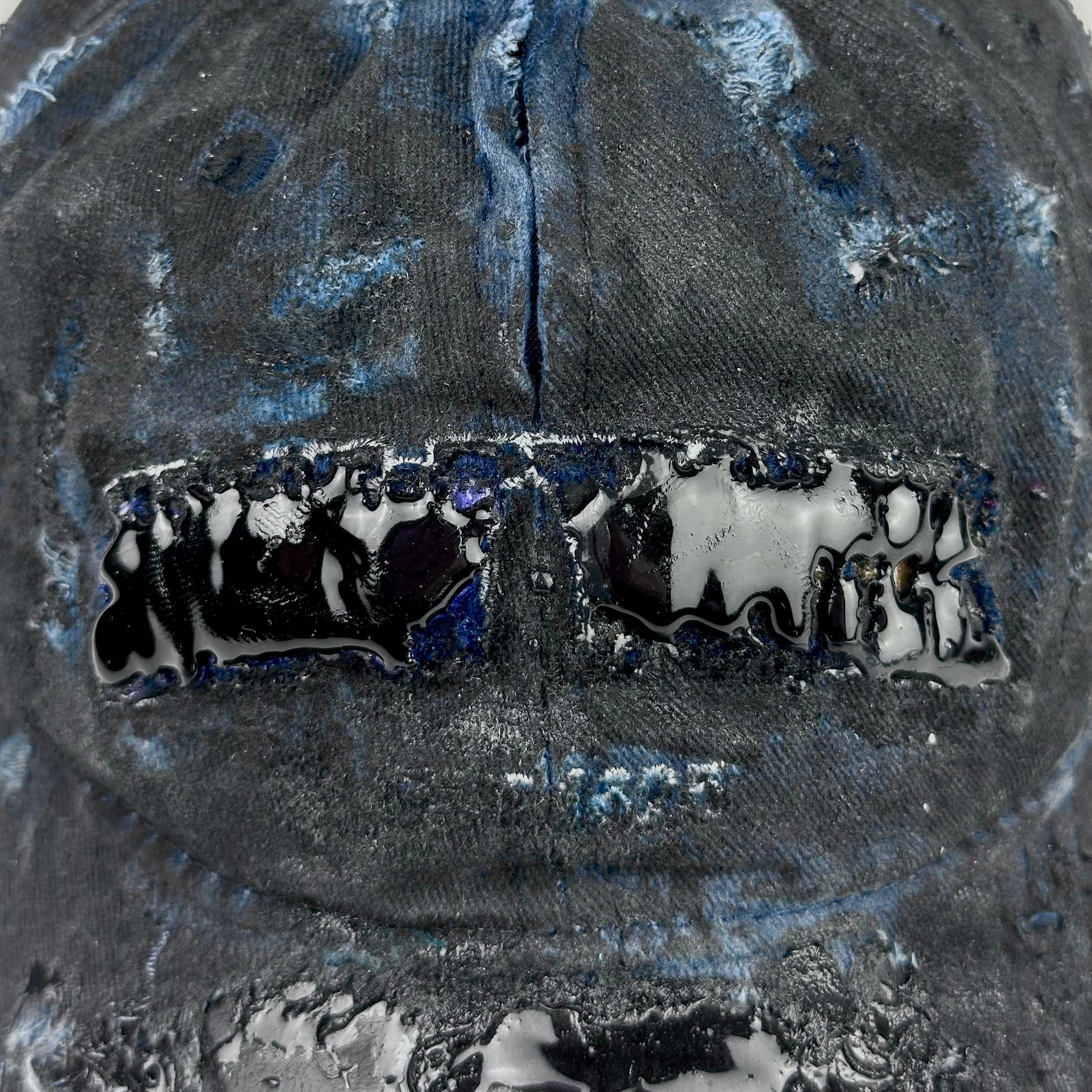 Logo detail on ASTROBOI* 'Feeling Blue' distressed blue resin-coated hat with hand-painted black shading, metal piercings on the right front, and New York embroidery, handmade in NYC.