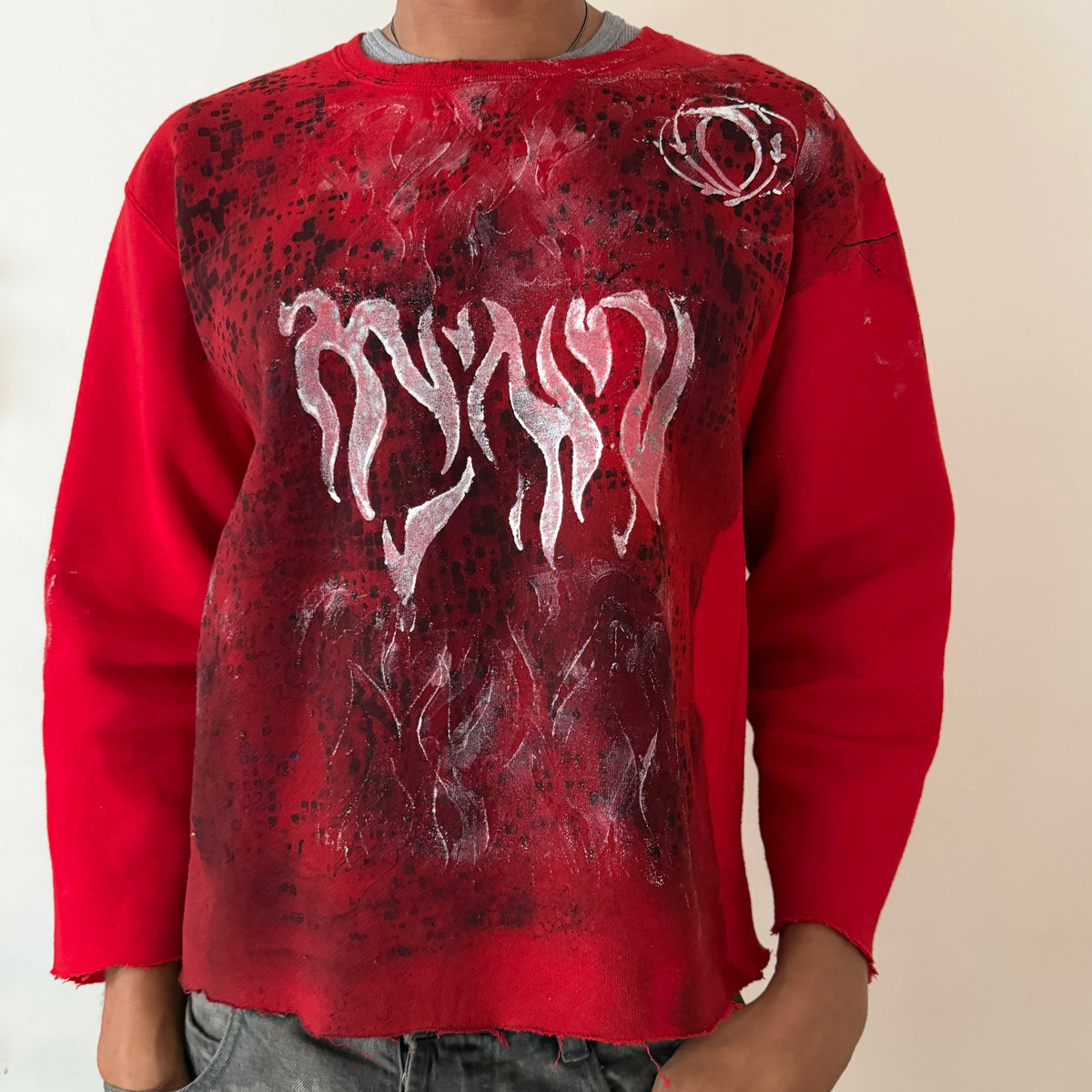 Close-up of ASTROBOI* x Russell ‘Red Wave’ showing washed out black digital camo print and white Y2K flame winged design layered on red cotton fabric.