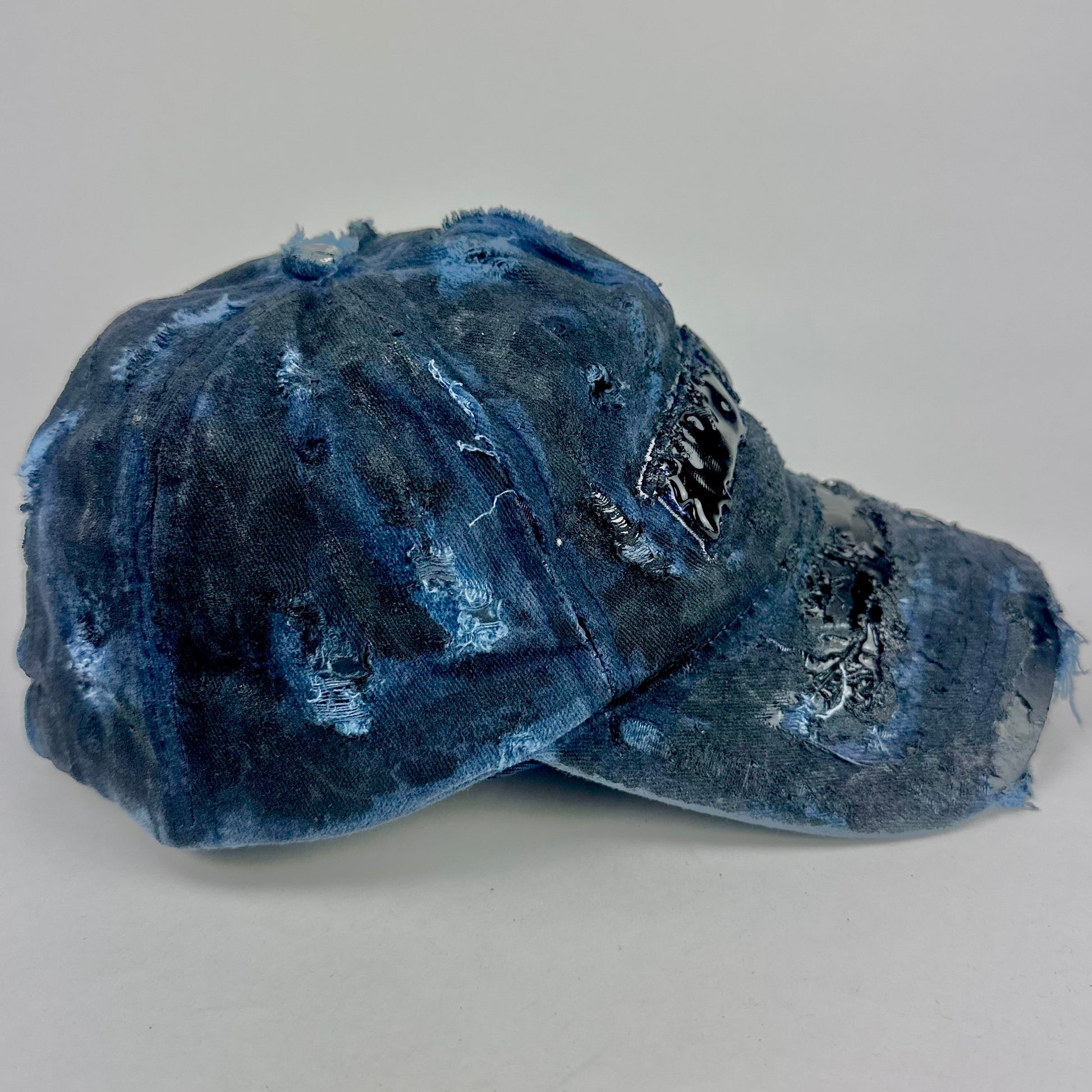 Right side of ASTROBOI* 'Feeling Blue' distressed blue resin-coated hat with hand-painted black shading, metal piercings on the right front, and New York embroidery, handmade in NYC.