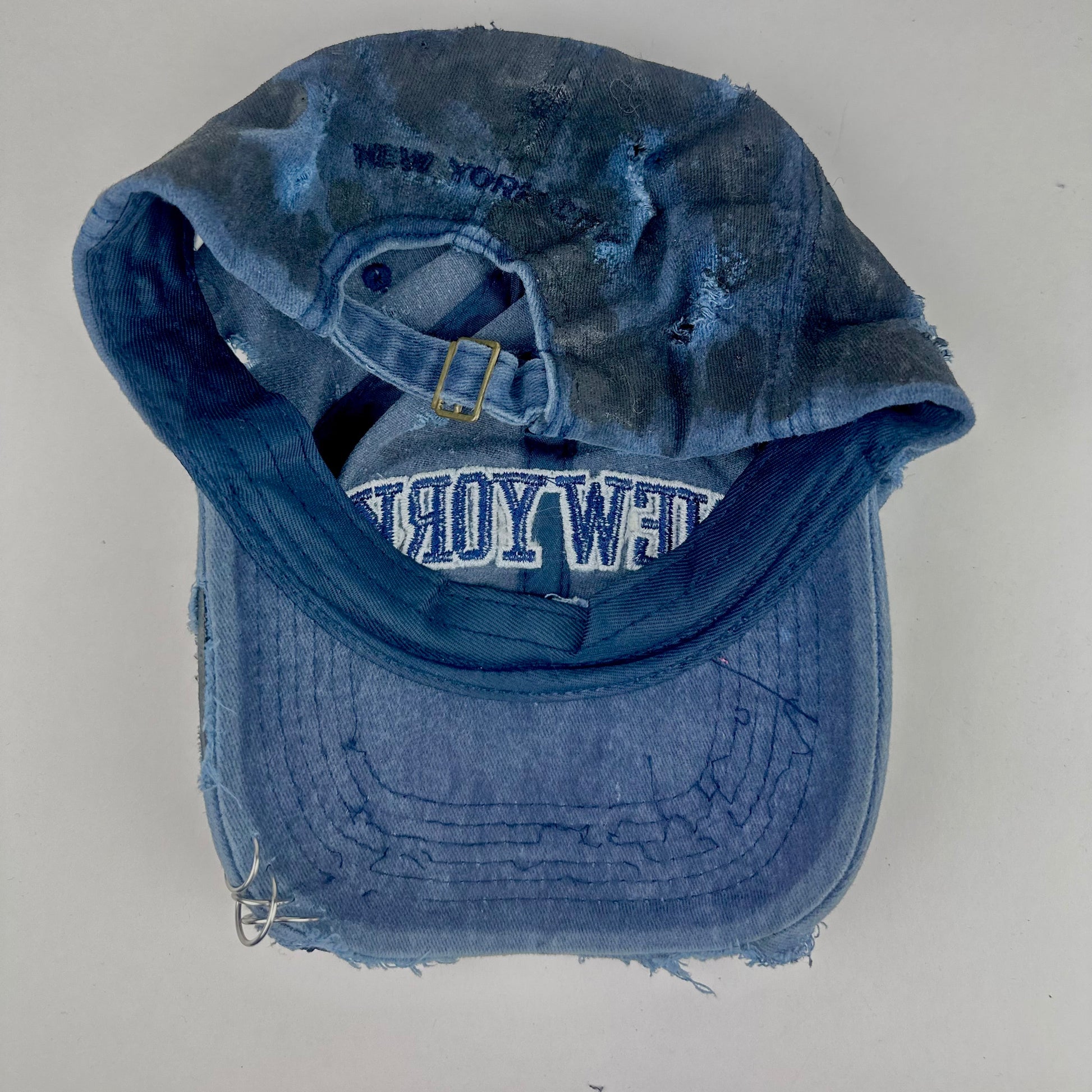 Back of ASTROBOI* 'Feeling Blue' distressed blue resin-coated hat with hand-painted black shading, metal piercings on the right front, and New York embroidery, handmade in NYC.