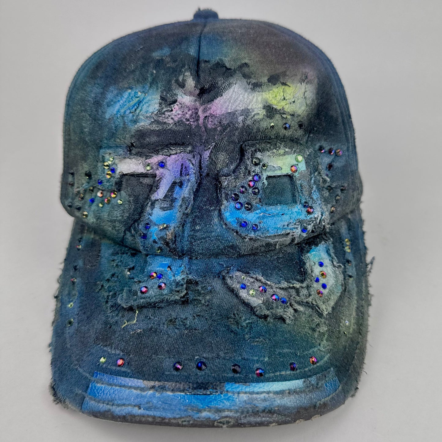 Front of ASTROBOI* 'Tropical 79' upcycled Y2K distressed hat featuring rainbow paint design, multicolored rhinestone embellishments, and hand-painted black shading for contrast, on a neutral background.