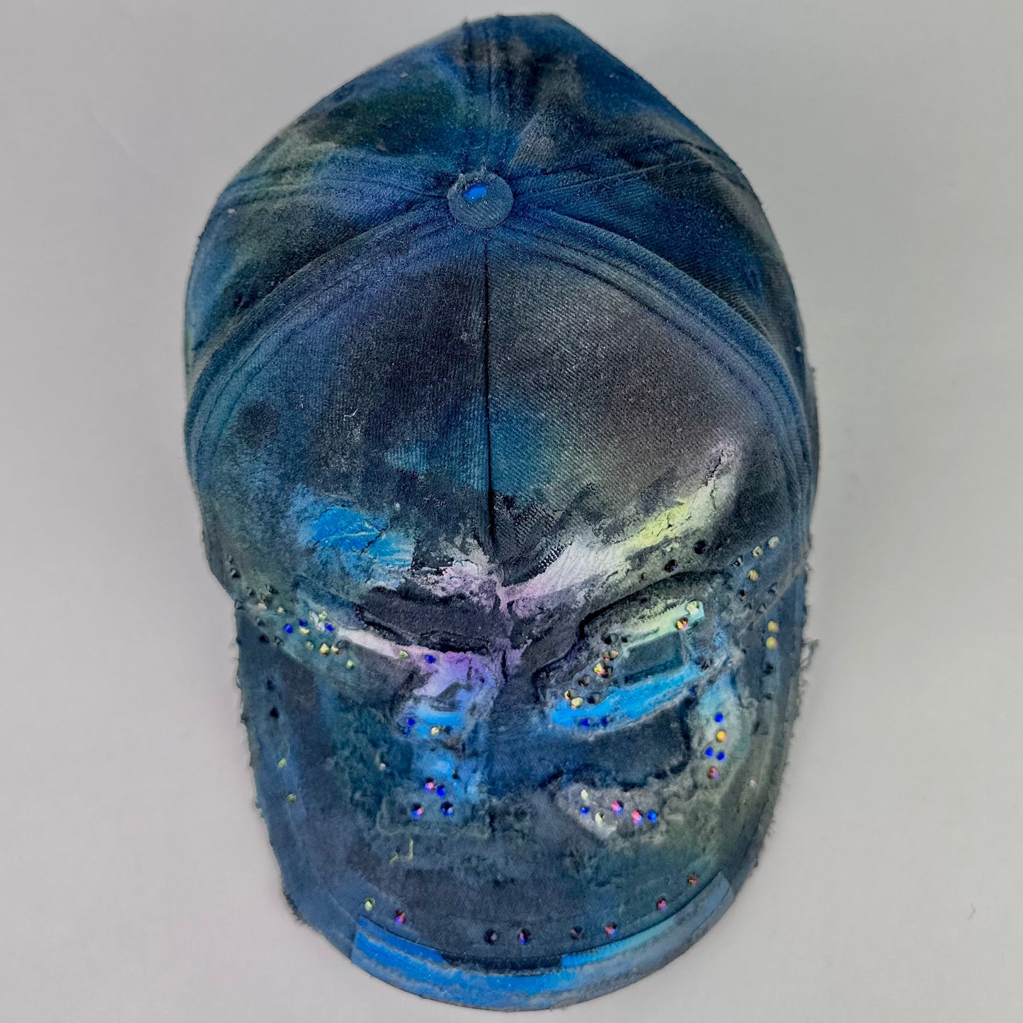 Top of ASTROBOI* 'Tropical 79' upcycled Y2K distressed hat featuring rainbow paint design, multicolored rhinestone embellishments, and hand-painted black shading for contrast, on a neutral background.