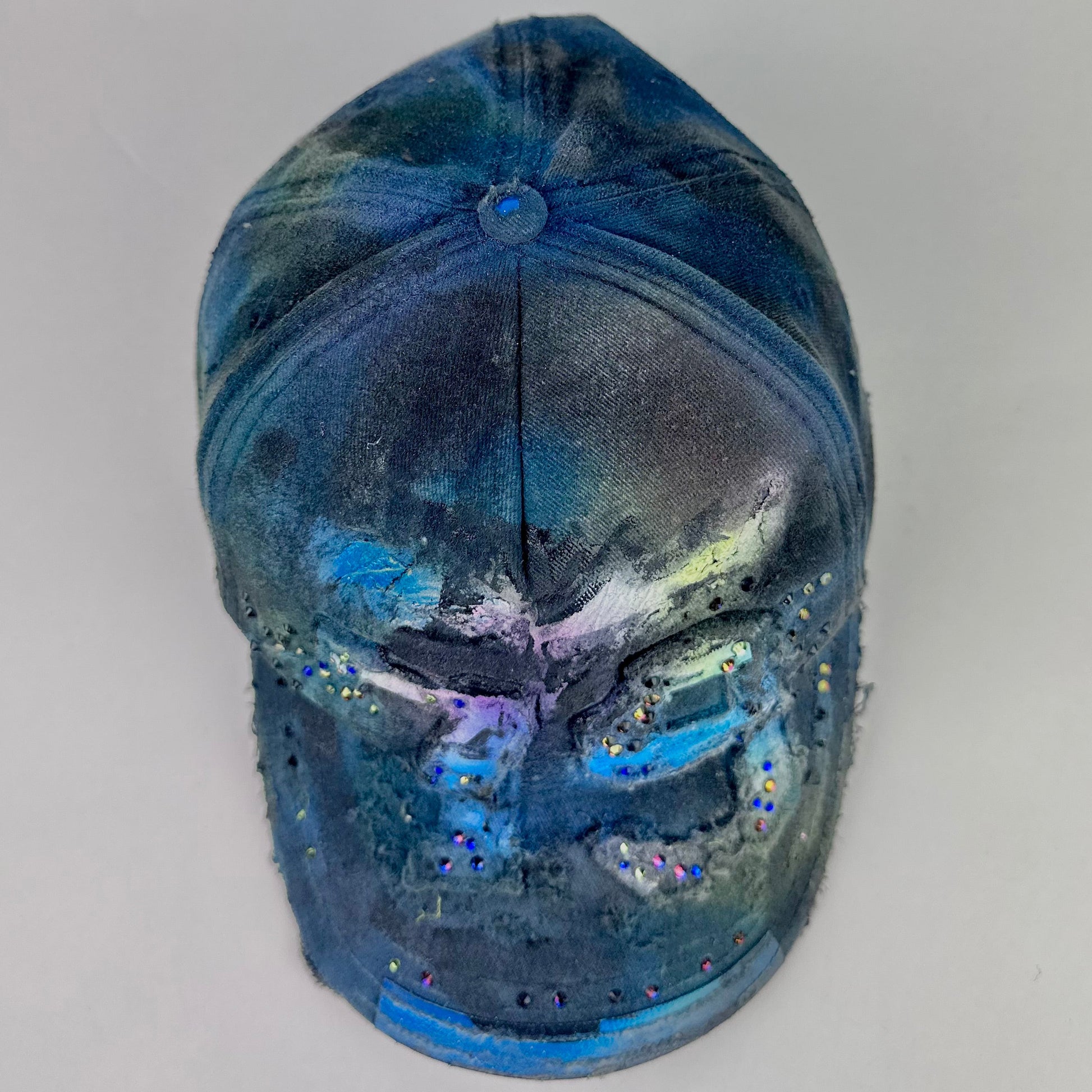 Top of ASTROBOI* 'Tropical 79' upcycled Y2K distressed hat featuring rainbow paint design, multicolored rhinestone embellishments, and hand-painted black shading for contrast, on a neutral background.