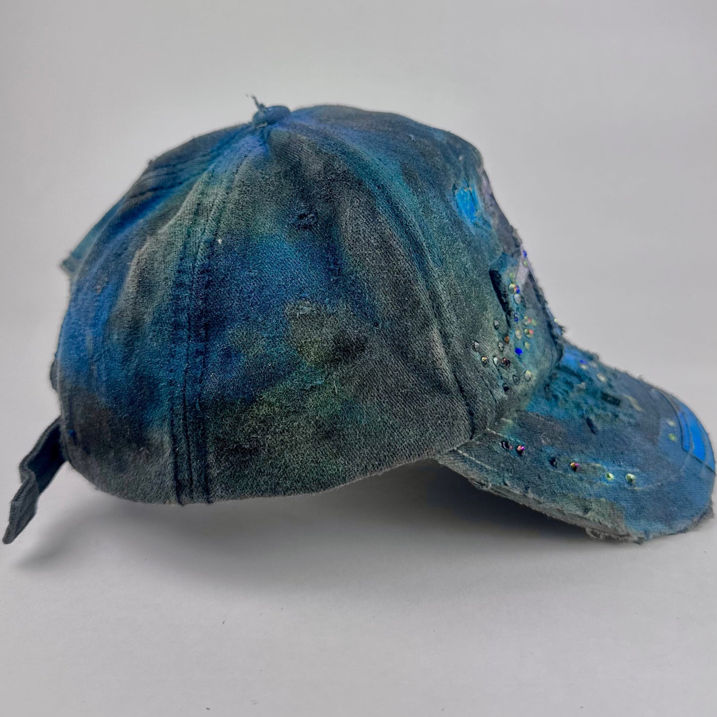 Right side of ASTROBOI* 'Tropical 79' upcycled Y2K distressed hat featuring rainbow paint design, multicolored rhinestone embellishments, and hand-painted black shading for contrast, on a neutral background.