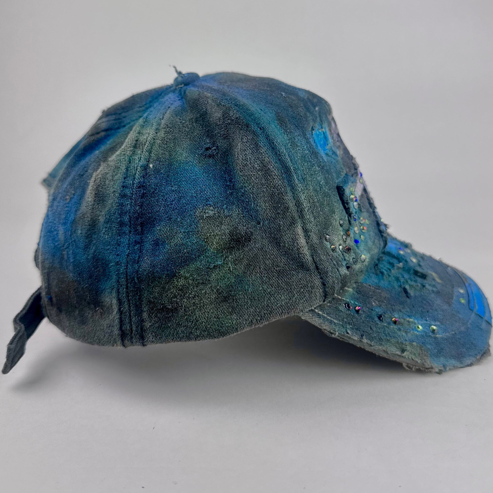 Right side of ASTROBOI* 'Tropical 79' upcycled Y2K distressed hat featuring rainbow paint design, multicolored rhinestone embellishments, and hand-painted black shading for contrast, on a neutral background.