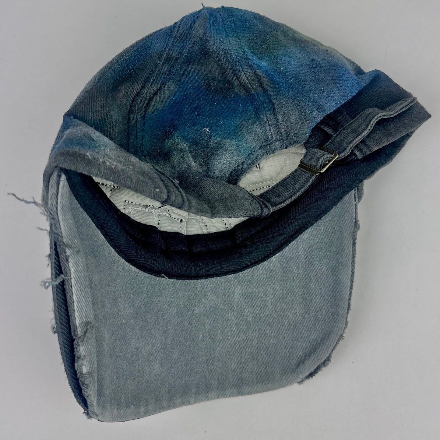 Back of ASTROBOI* 'Tropical 79' upcycled Y2K distressed hat featuring rainbow paint design, multicolored rhinestone embellishments, and hand-painted black shading for contrast, on a neutral background.