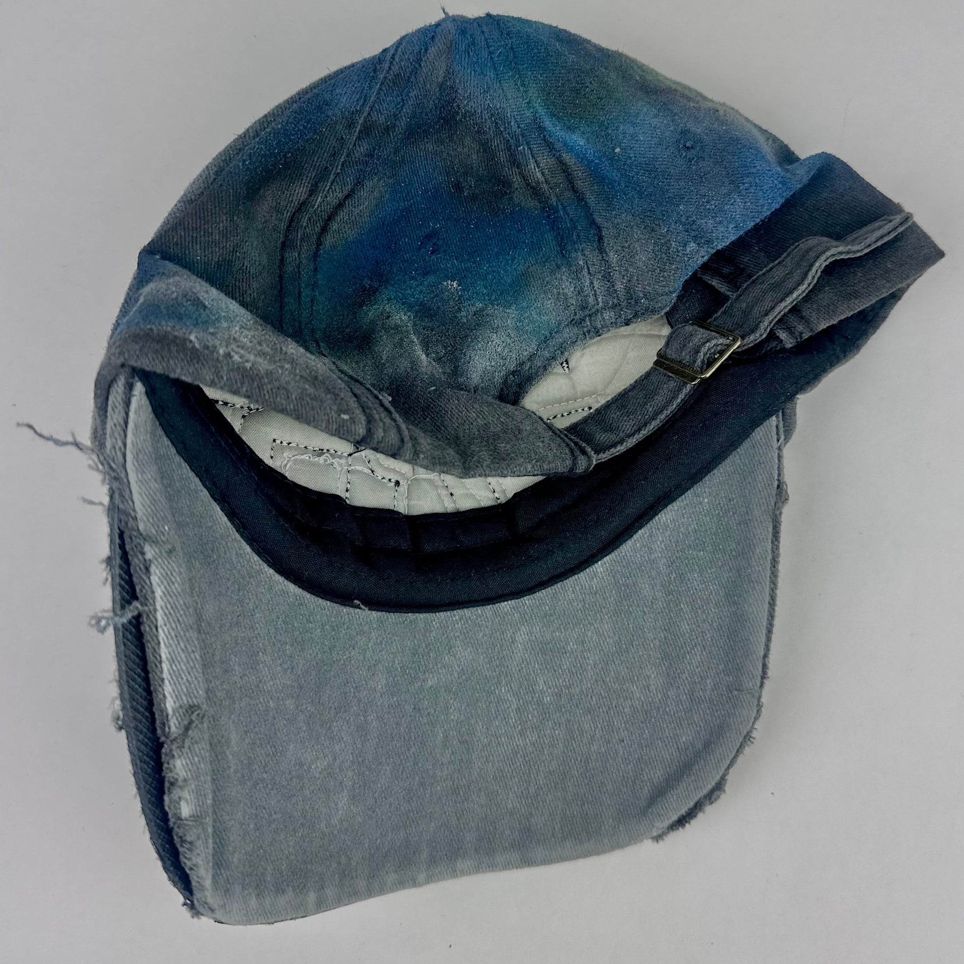 Back of ASTROBOI* 'Tropical 79' upcycled Y2K distressed hat featuring rainbow paint design, multicolored rhinestone embellishments, and hand-painted black shading for contrast, on a neutral background.