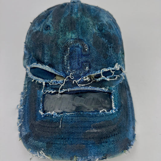 Front of ASTROBOI* 'C' deconstructed black and blue faded denim hat with hand-painted blue-green shading, raw crown cut-outs, and embossed C logo at center front, customized in NYC.