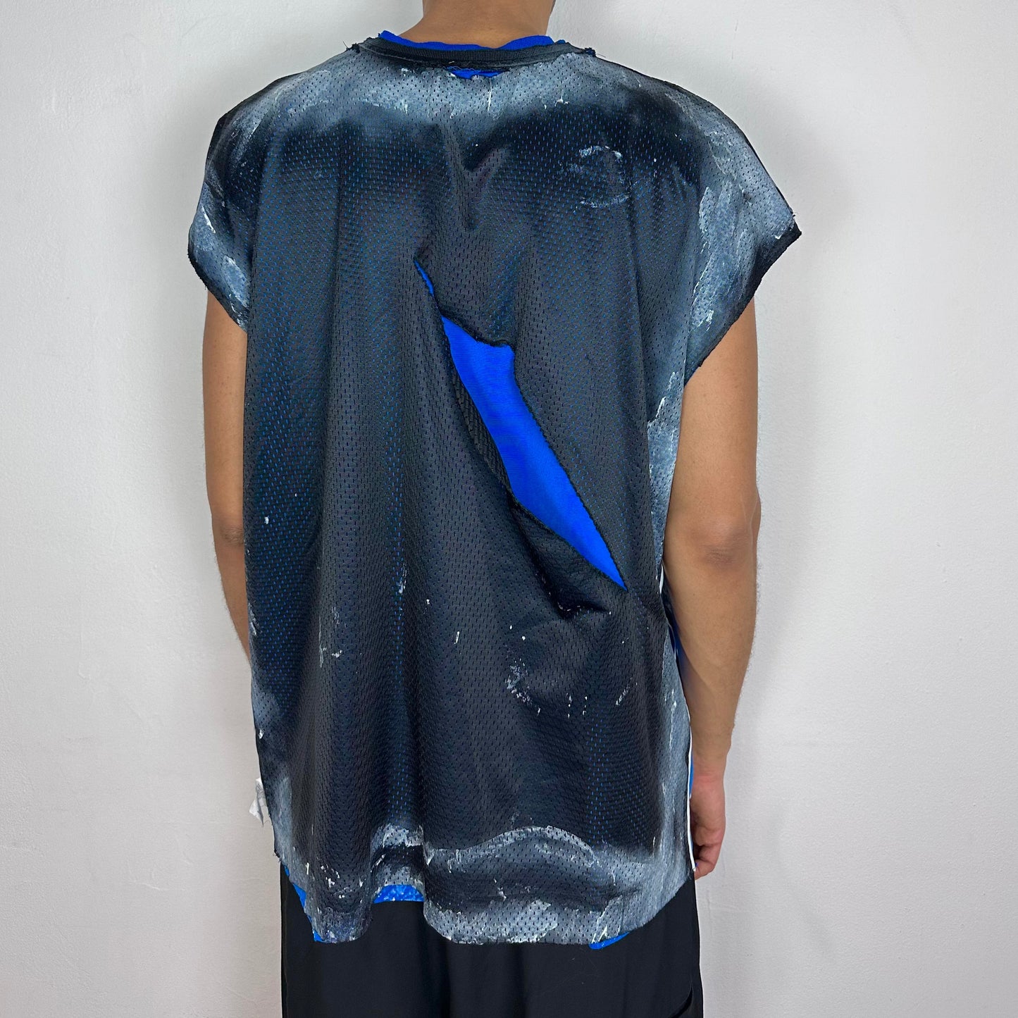 Back - ASTROBOI* x Starter black and blue ripped mesh tank top, rear view showing ripped mesh construction and white paint detailing, worn by male model.