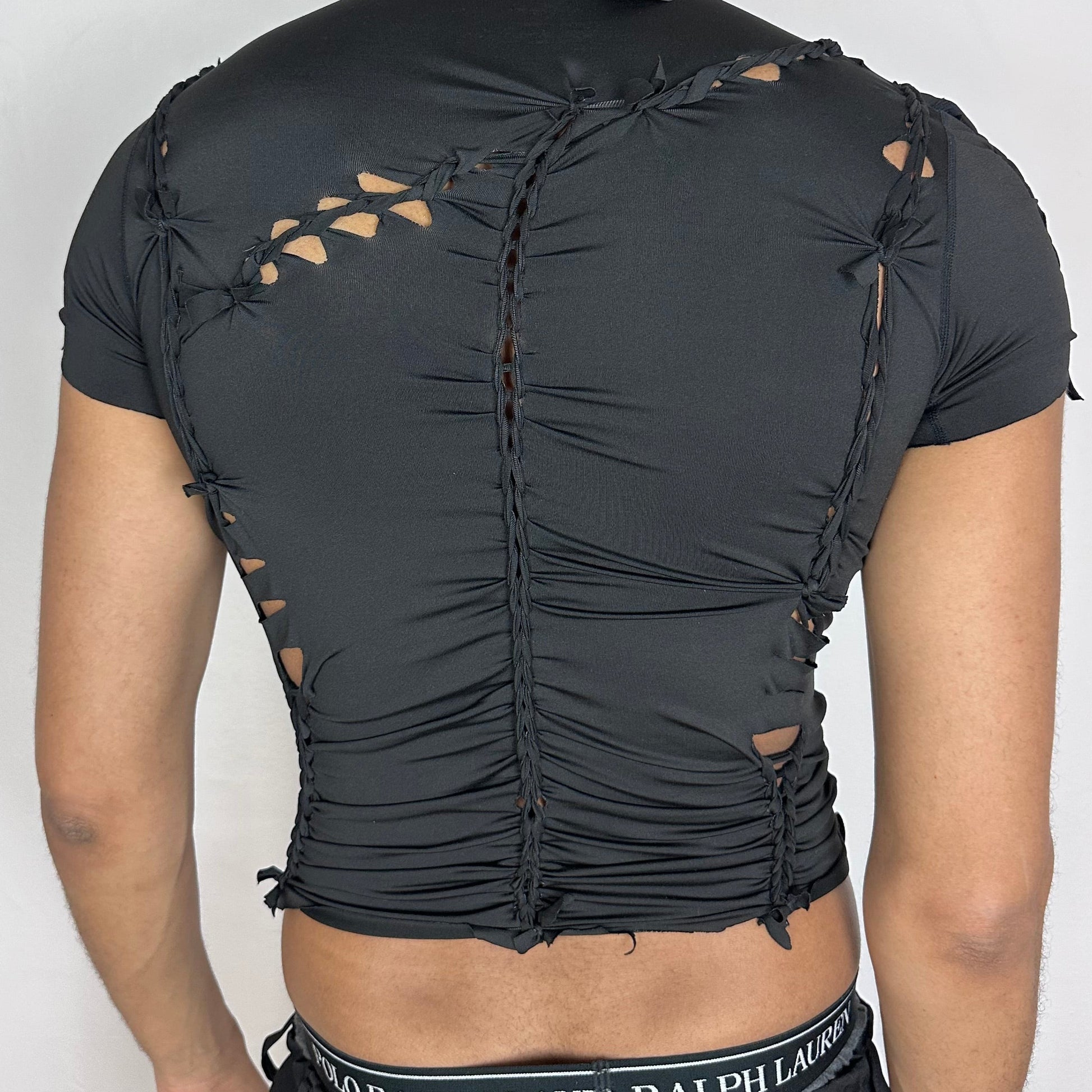 ASTROBOI* 'Pandora' black short sleeve braided compression crop top, rear view showing braid and cut-out construction, worn by male model.